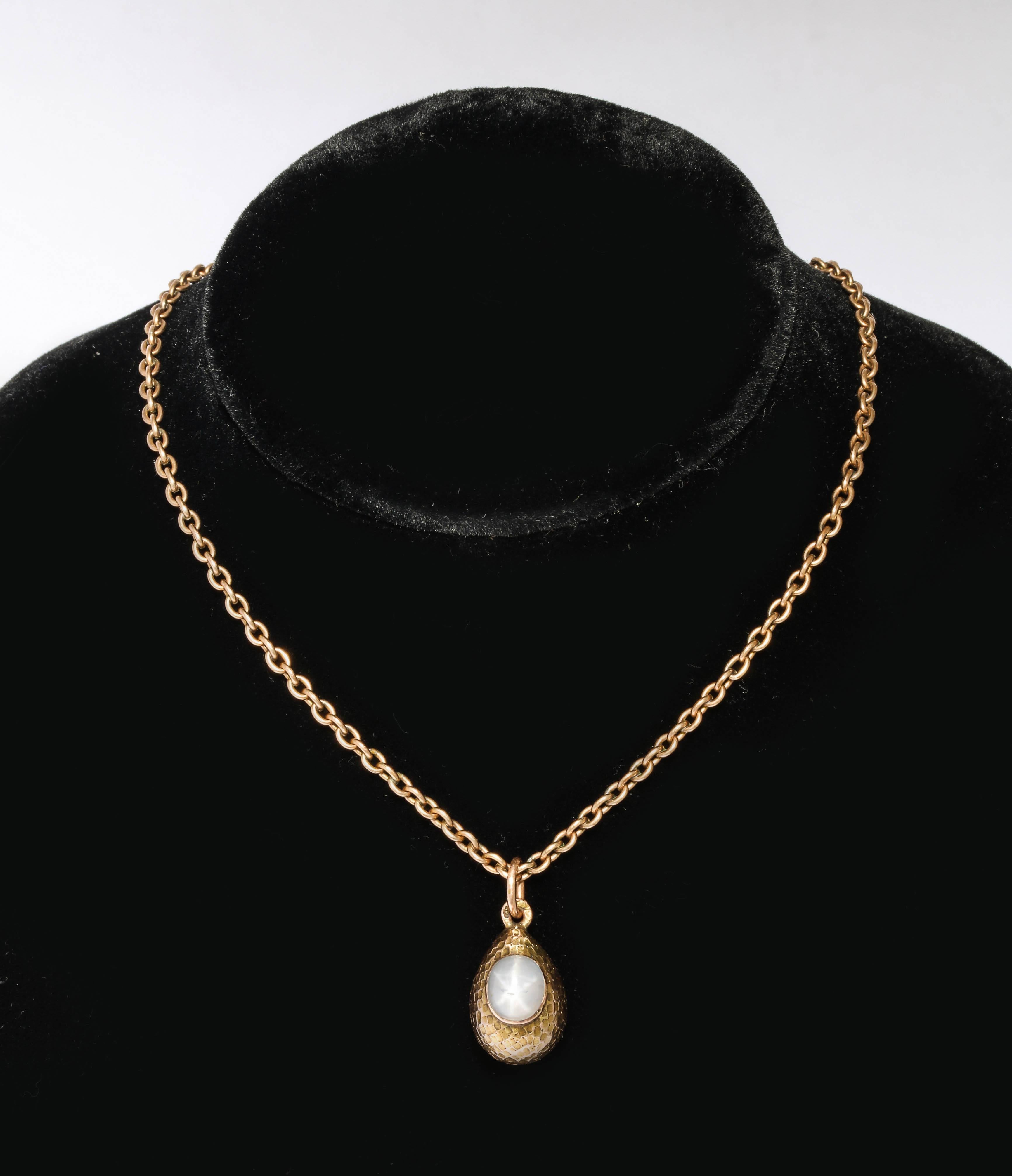 From the Romanov era, period of Tsar Nicholas II, of hammered rose gold enhanced with an oval high-cut sugarloaf cabochon star sapphire weighing approx 3.07 cts. Completely original and fitted with a gold suspension ring. Chain not included. 

The