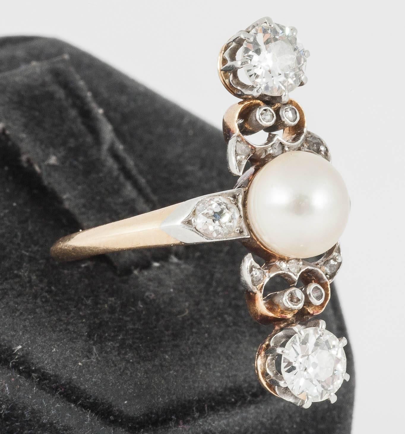 A silver and gold mounted down the finger ring set with a central,oriental [ natural] pearl,two,brilliant cut diamonds,each weighing approx 0.30carats, with brilliant cut diamond to each shoulder,and rose cut diamonds between ,French