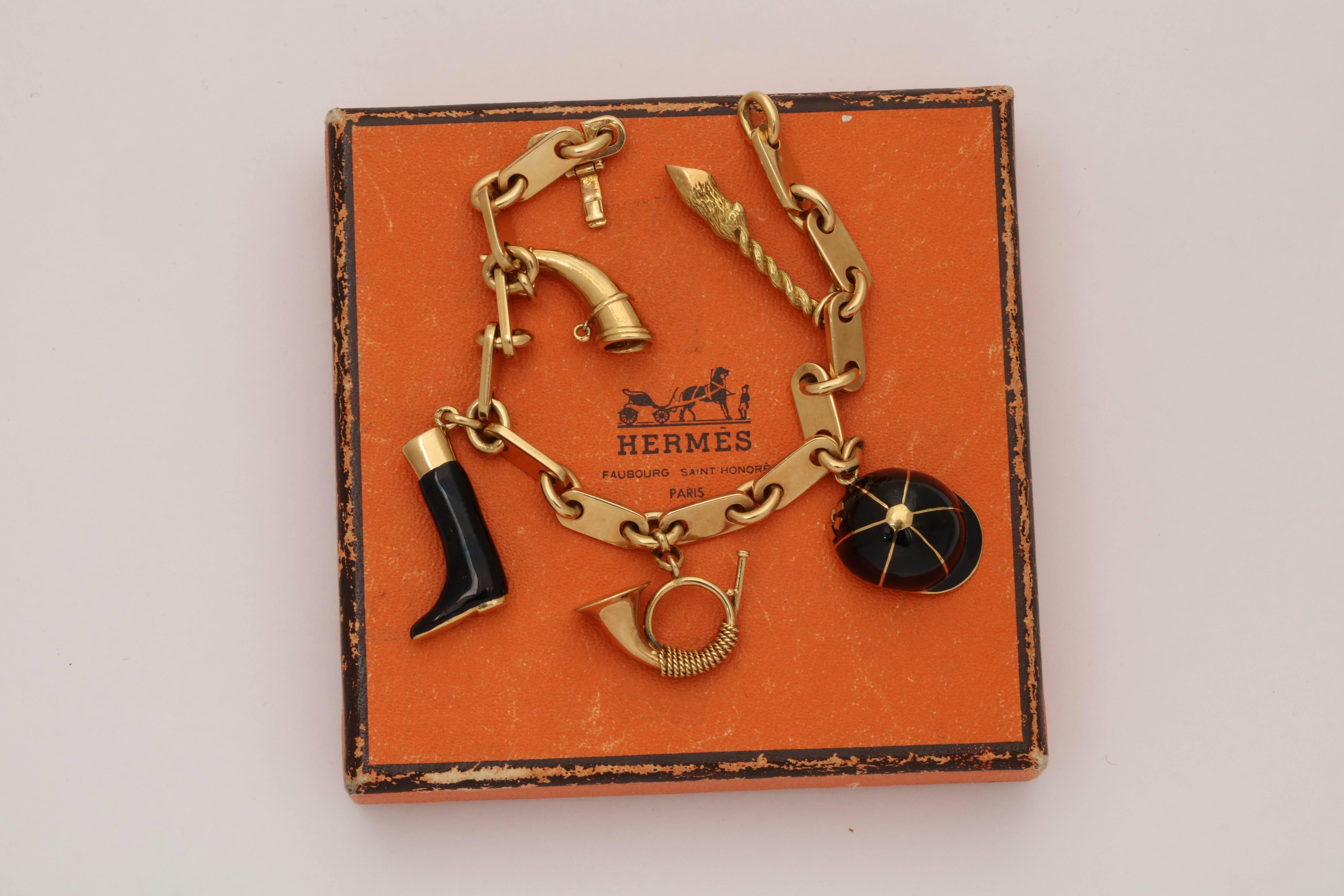 Hermes Paris Equestrian And Musical Motif 18kt Gold Charm Bracelet Consisting Of Alternating Equestrian Type Charms In Black Enamel And Two 18kt Musical Related Charms With One Fish With Scales Charm in 18kt Yellow Gold. All Attached To A Beautiful