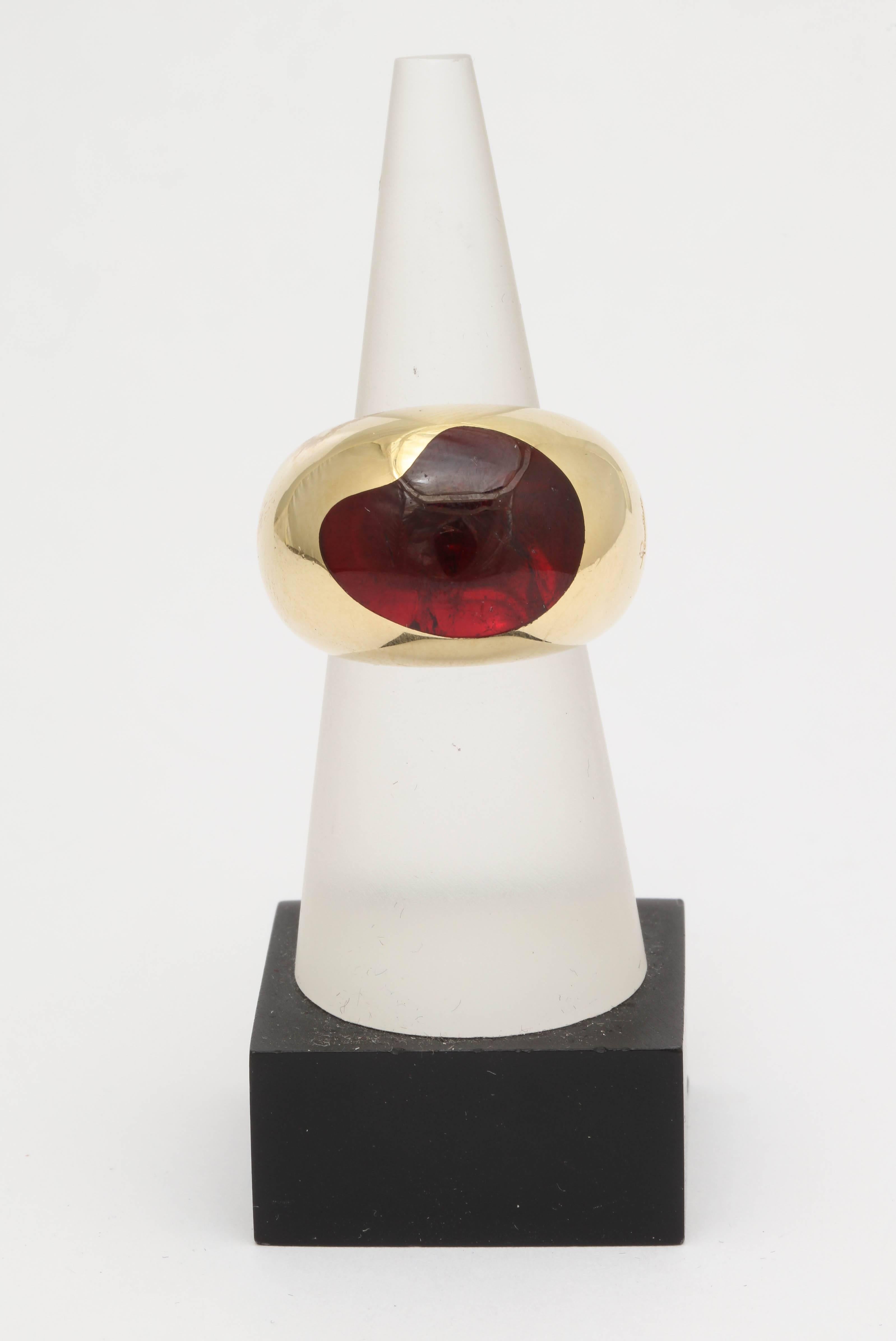 One Unisex Ring Composed Of One Unusually Aysmmetrical Shaped Beautiful Color Cabochon Garnet Heavy 18kt gold Ring. Designed By Pomellato Jewelers In The 1990's. Ring Currently Size 6.5 And May Easily Be Resized.