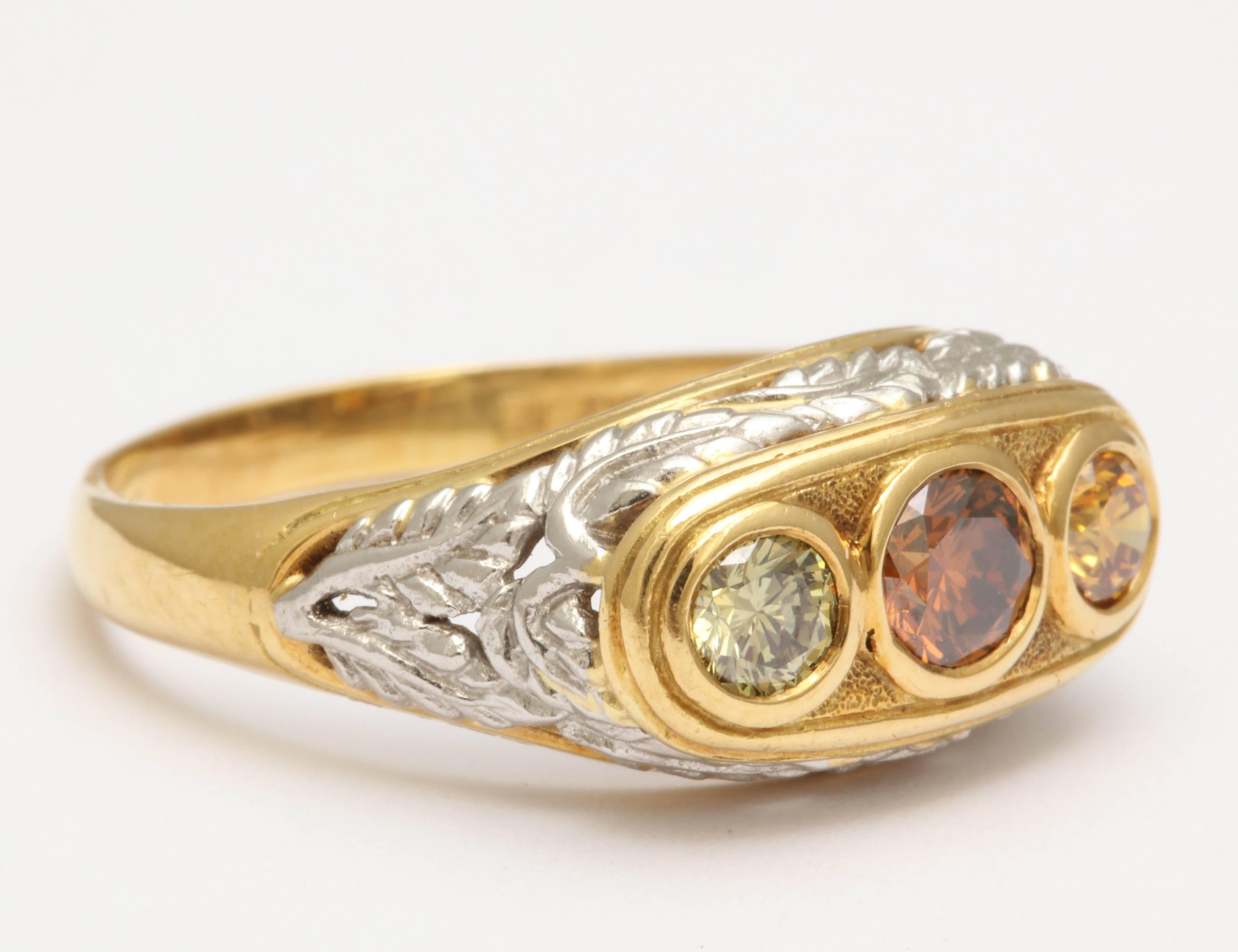 This 18Kt yellow gold hand made, one of a kind,mounting with platinum leaf design. The ring holds a .42 ct orange-brown diamond with a .30ct yellow- green diamond on one side and a .32 ct yellow-orange on the other side. The diamonds are not treated