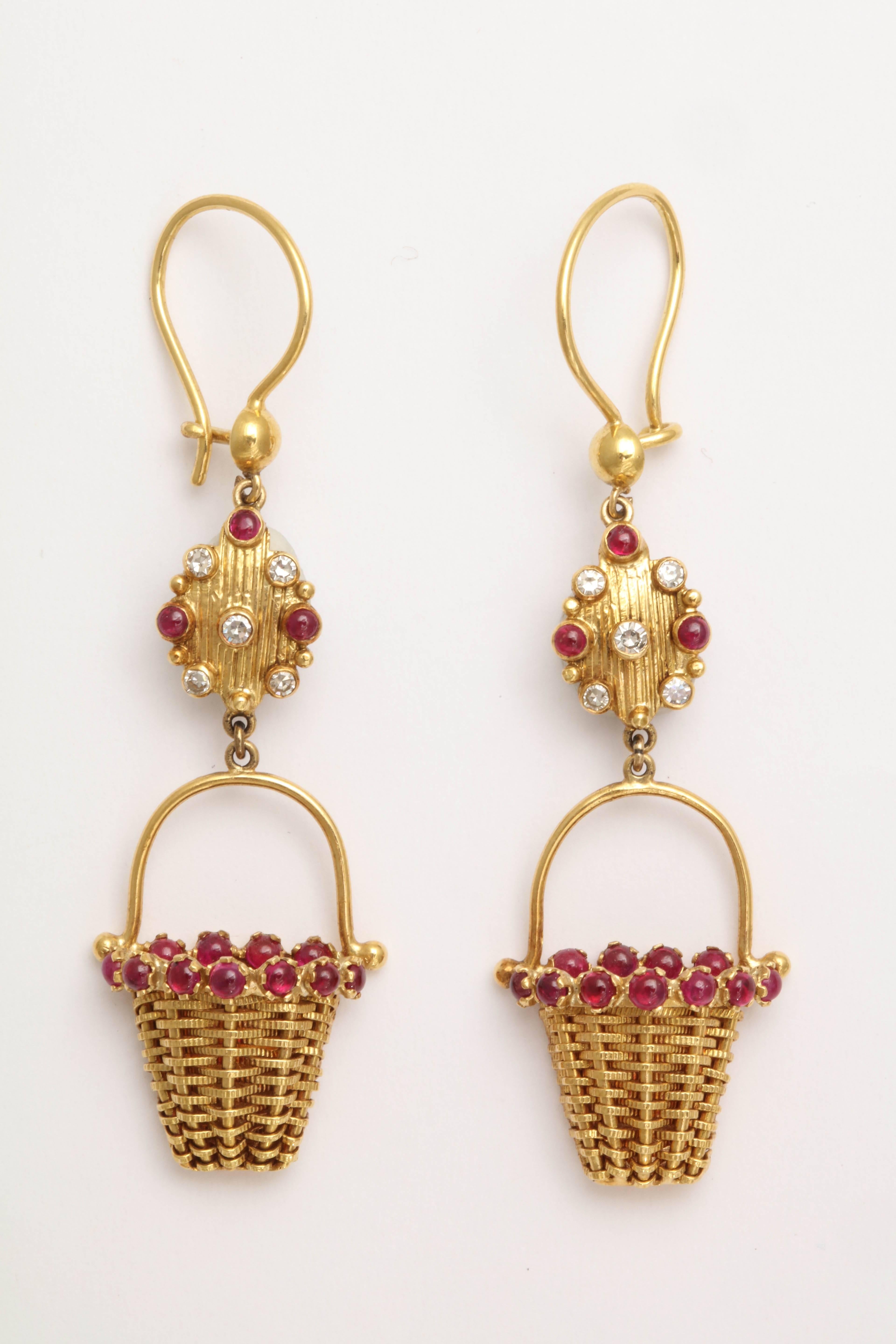 These are hand woven baskets in a textured 18 kt gold wire. The top is surrounded with beautiful ruby cabochons. The engraved link between the basket and the ear wire is decorated  with ruby cabochons and faceted diamonds. The ear wire has a safety