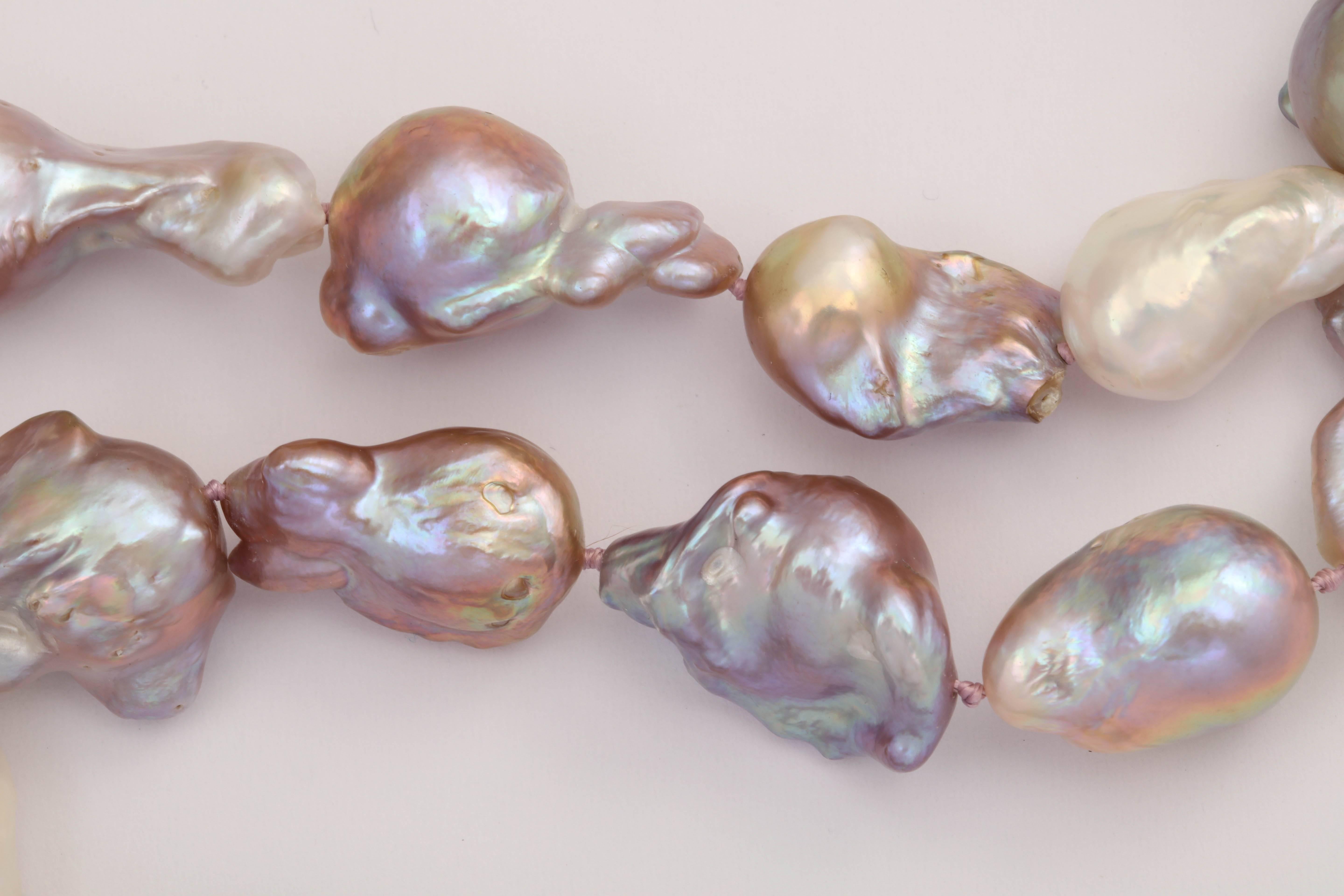 This strand of baroque fresh water pearls are a spectacular combination of pink, lilac, gold, blues and other natural tones. The total length is 33 inches and is finished with a filigree sterling silver ball clasp. Stringing guaranteed for 1 yr. of