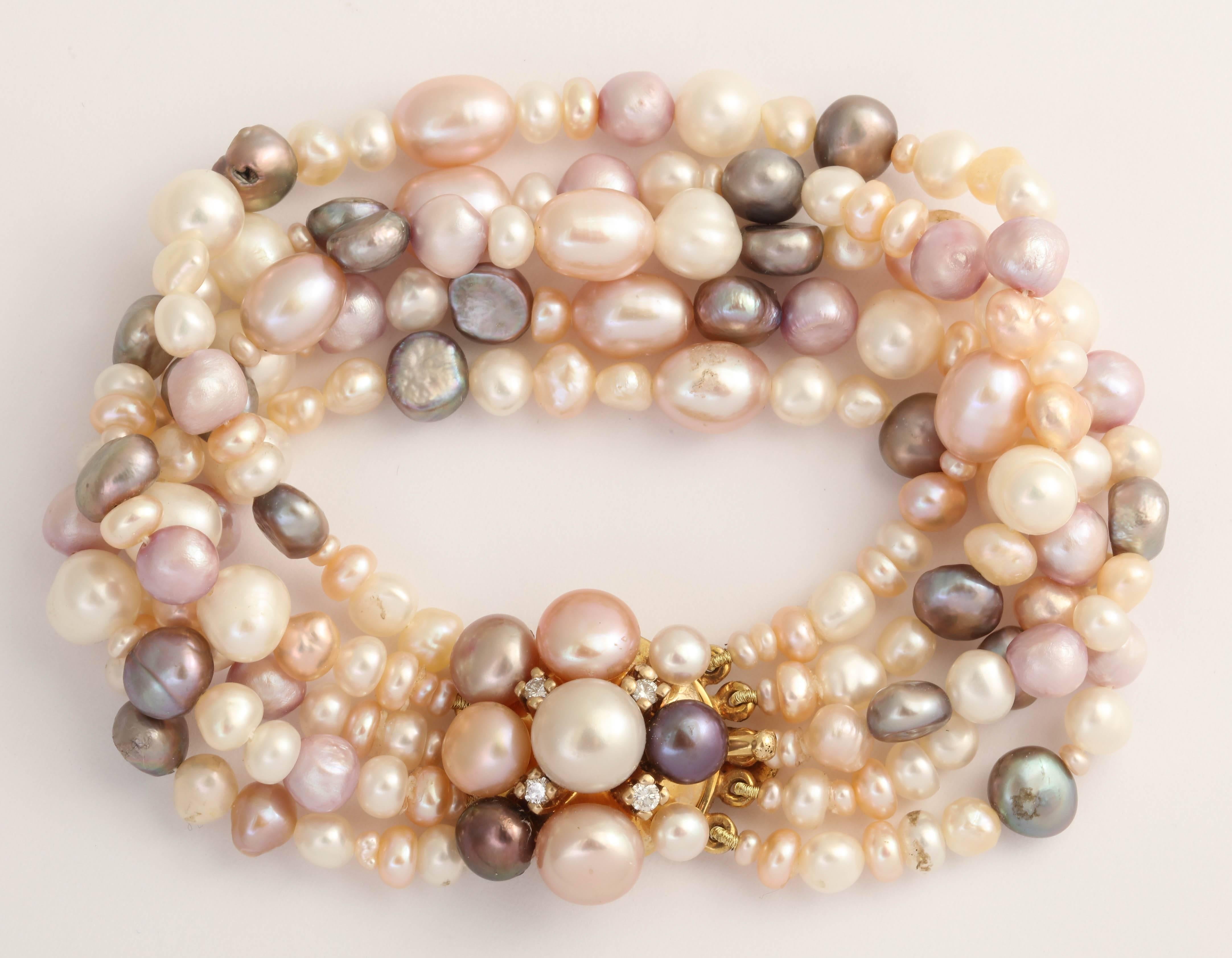 This delicious 5 strand combination of pink, peach, lilac, white and gray fresh water pearls compliments any skin tone. The clasp is a stunning circle of half drilled pearls that match the bracelet pearls and diamonds set in 14 Kt gold A necklace