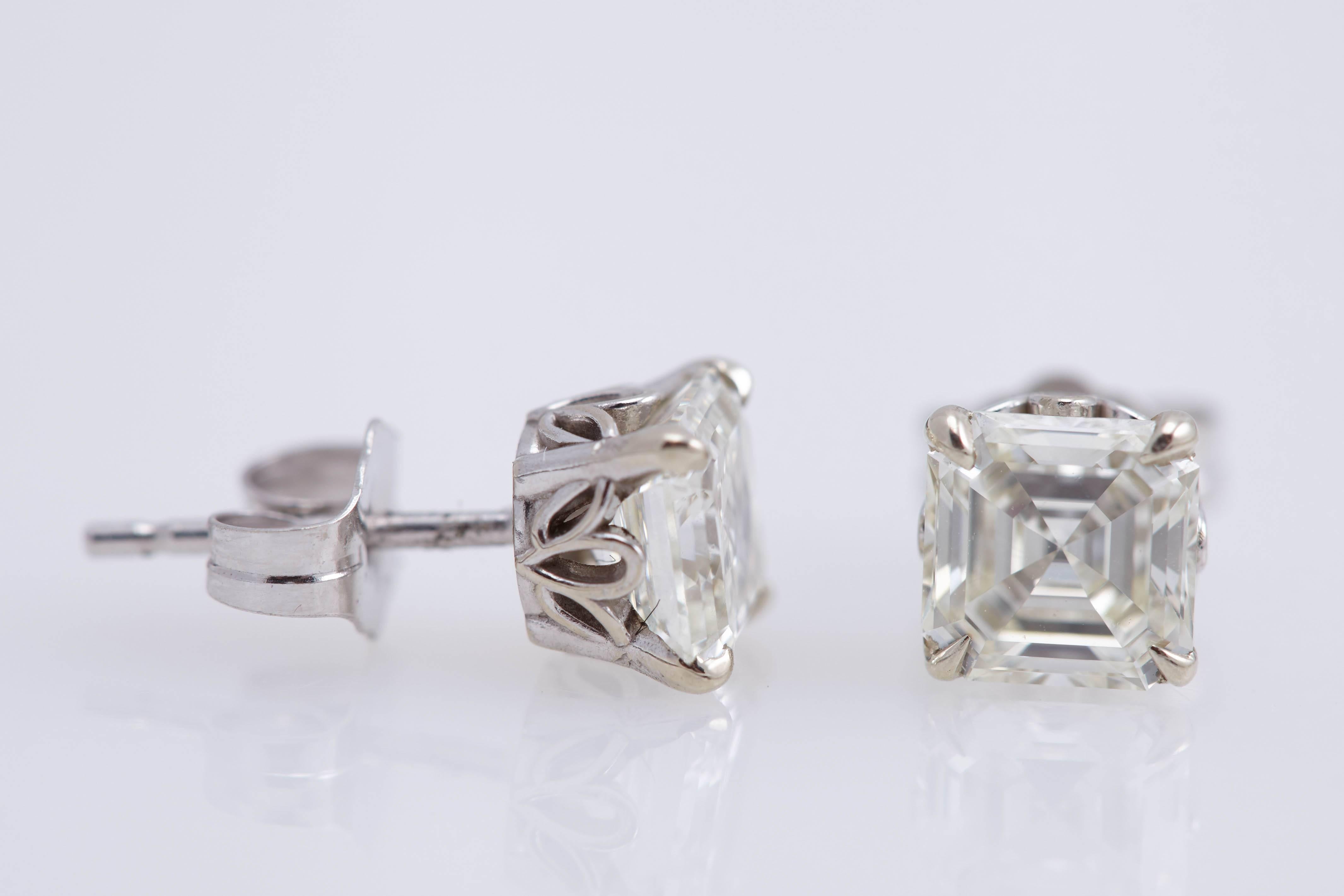 One pair of Asscher cut diamond earrings mounted in fourteen karat white gold. The diamonds have a total weight of approximately 1.68 carats. They are "I" in color and "VS" in clarity.