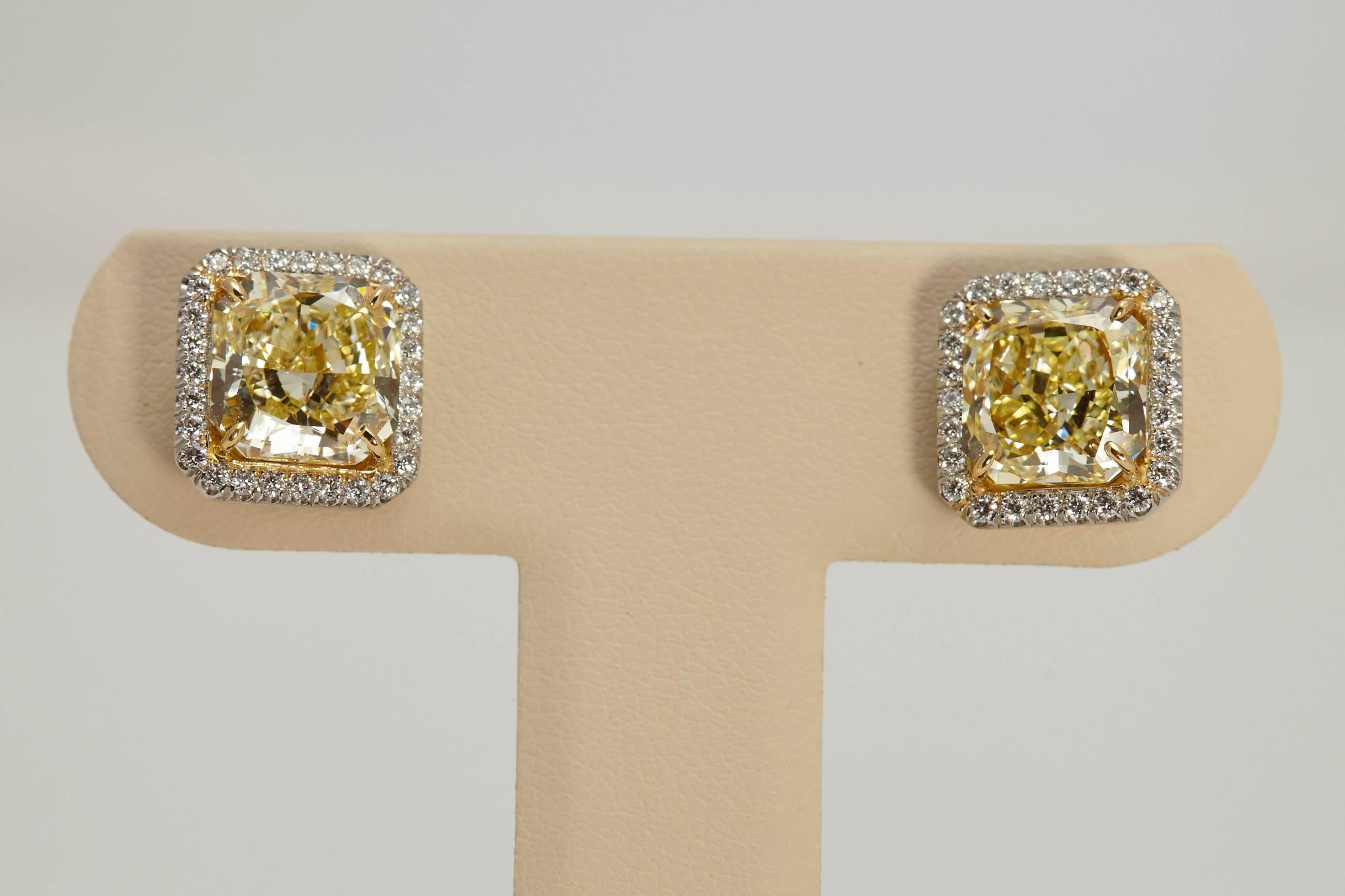 Pair of Fancy Yellow Radiant cut diamond earrings with a total weight of 6.61 carats in a halo setting surrounded by approximately  .45 carats of white diamonds. Set in platinum and 18 karat yellow gold. The diamonds weigh 3.22 carats and 3.39