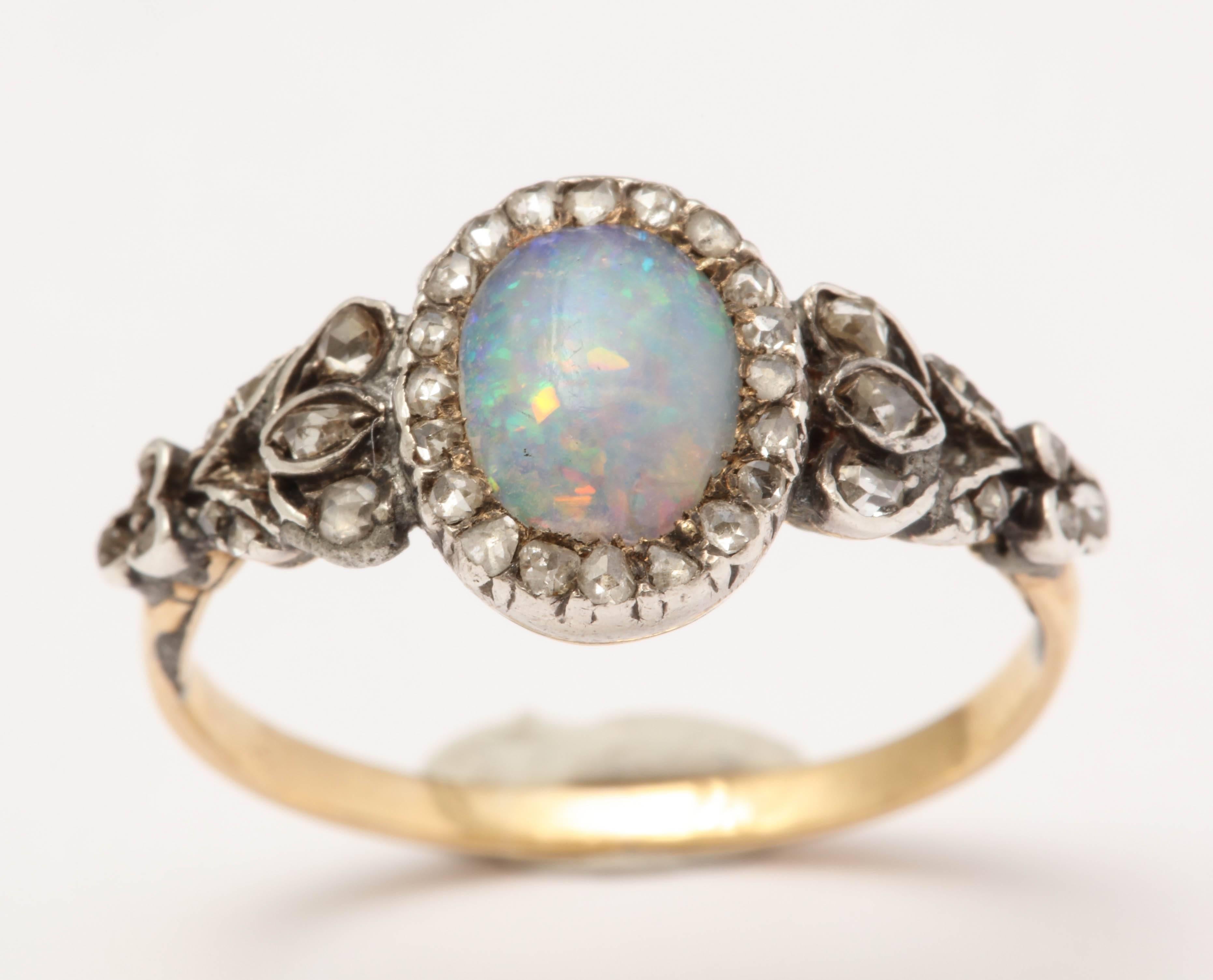 Beautiful opal surrounded with rosecut diamonds and rosecuts throughout the shoulders. Set in silver over yellow gold in closed back setting. 