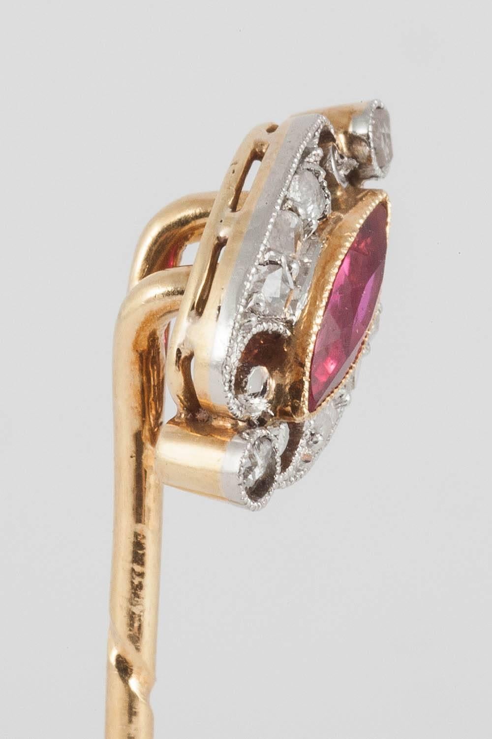 A good quality Burma Ruby of marquise shape in a surround of small rose cut diamonds, mounted as a tie pin, angled in design, set in platinum and 18 carat yellow gold.
Measures 10mm across.
Antique piece (over 100 years old) from the Edwardian