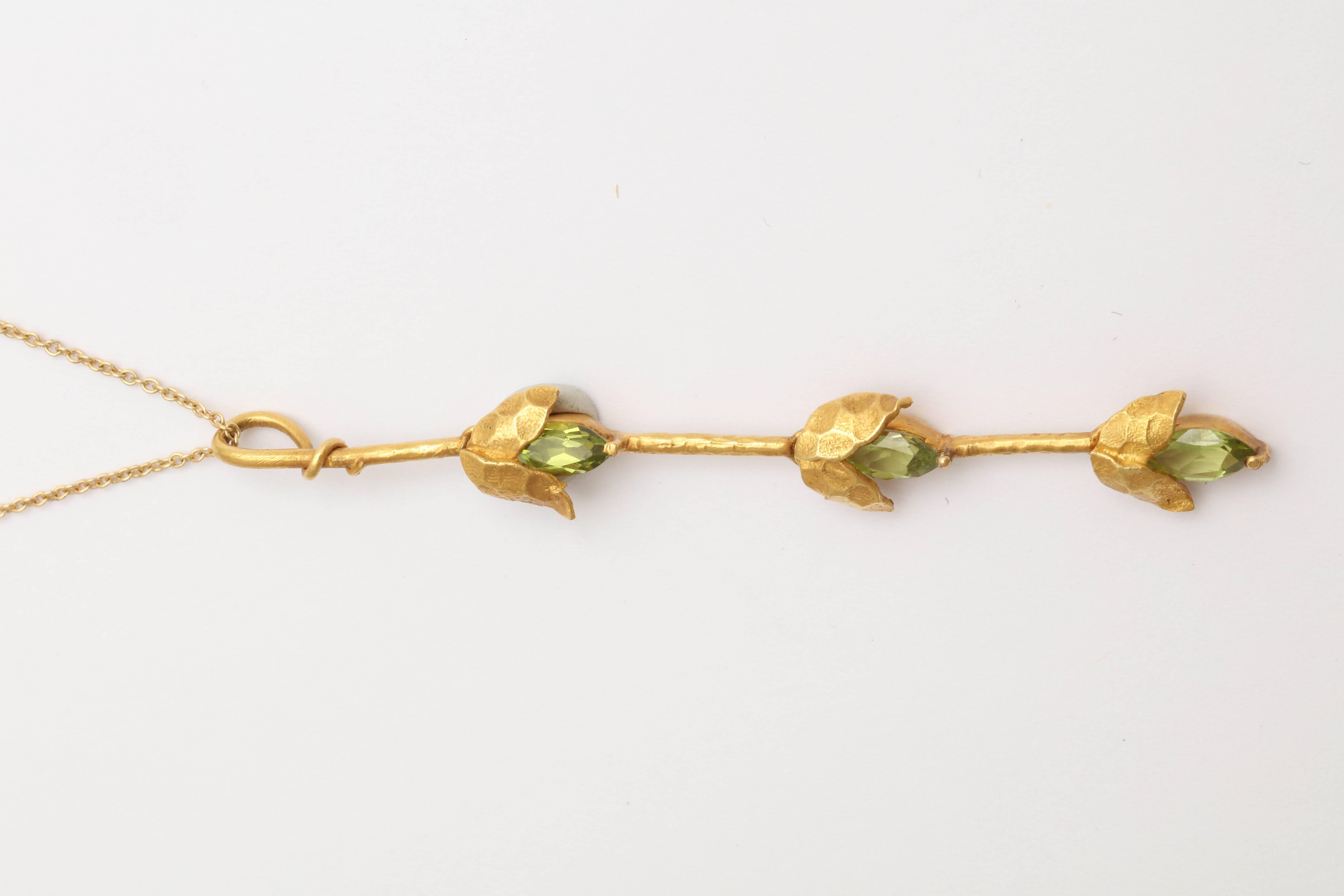 This set is made of 18 kt yellow gold in a matte hammered finish giving it an antient look. The gold leaves hold the peridot marquise and are articulated. The pendant is 3 in. long and the earrings are 2 3/4 in. long. The earrings hang from a 14 kt
