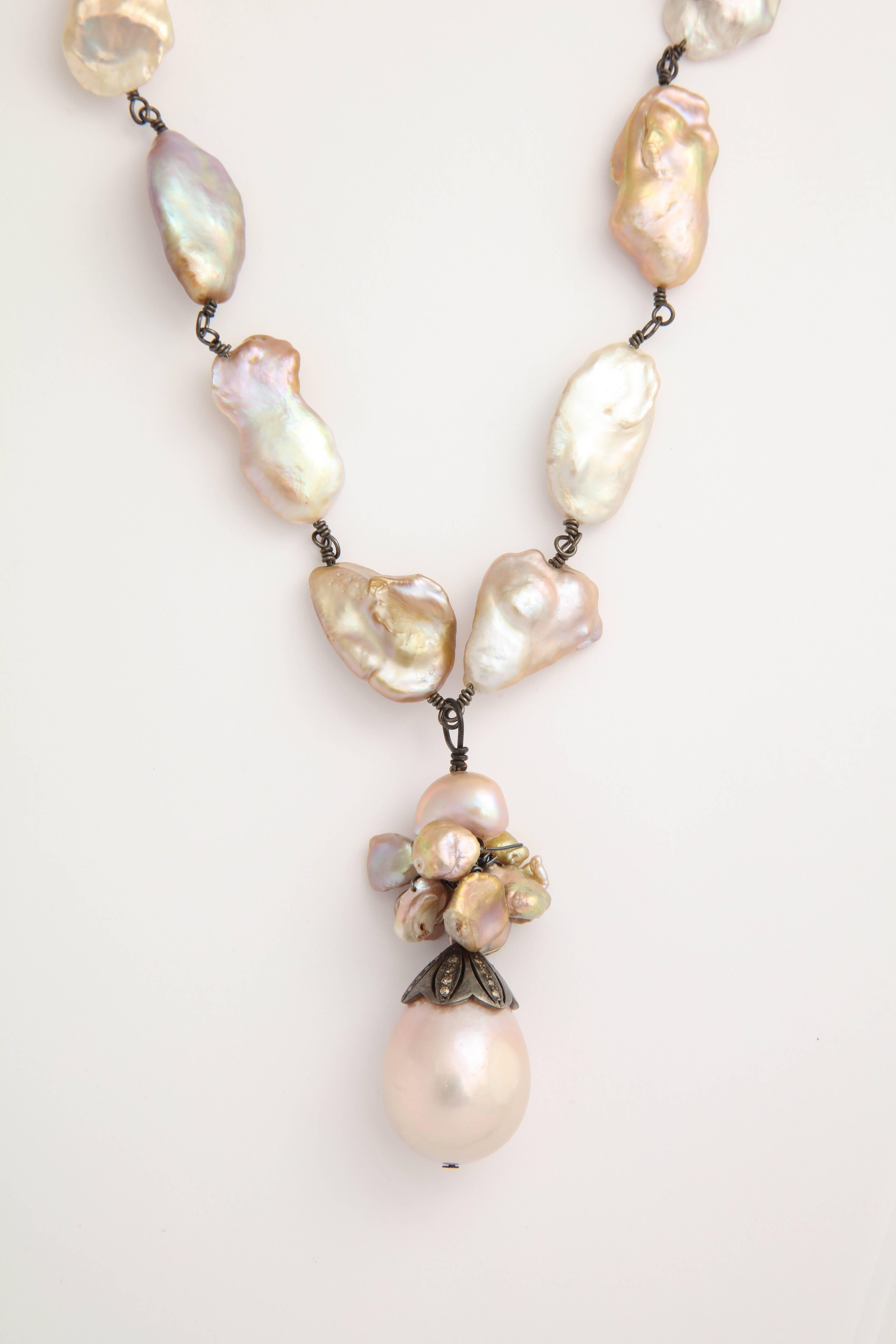 The oxidized silver wrapped necklace of pinkish baroque fresh water pearls is  36 in. long without the tassle. The tassle is made of smaller baroque pink pearl and a 3/4 in. X 1 in. pink pear shaped pearl topped by a silver and diamond pearl cap.