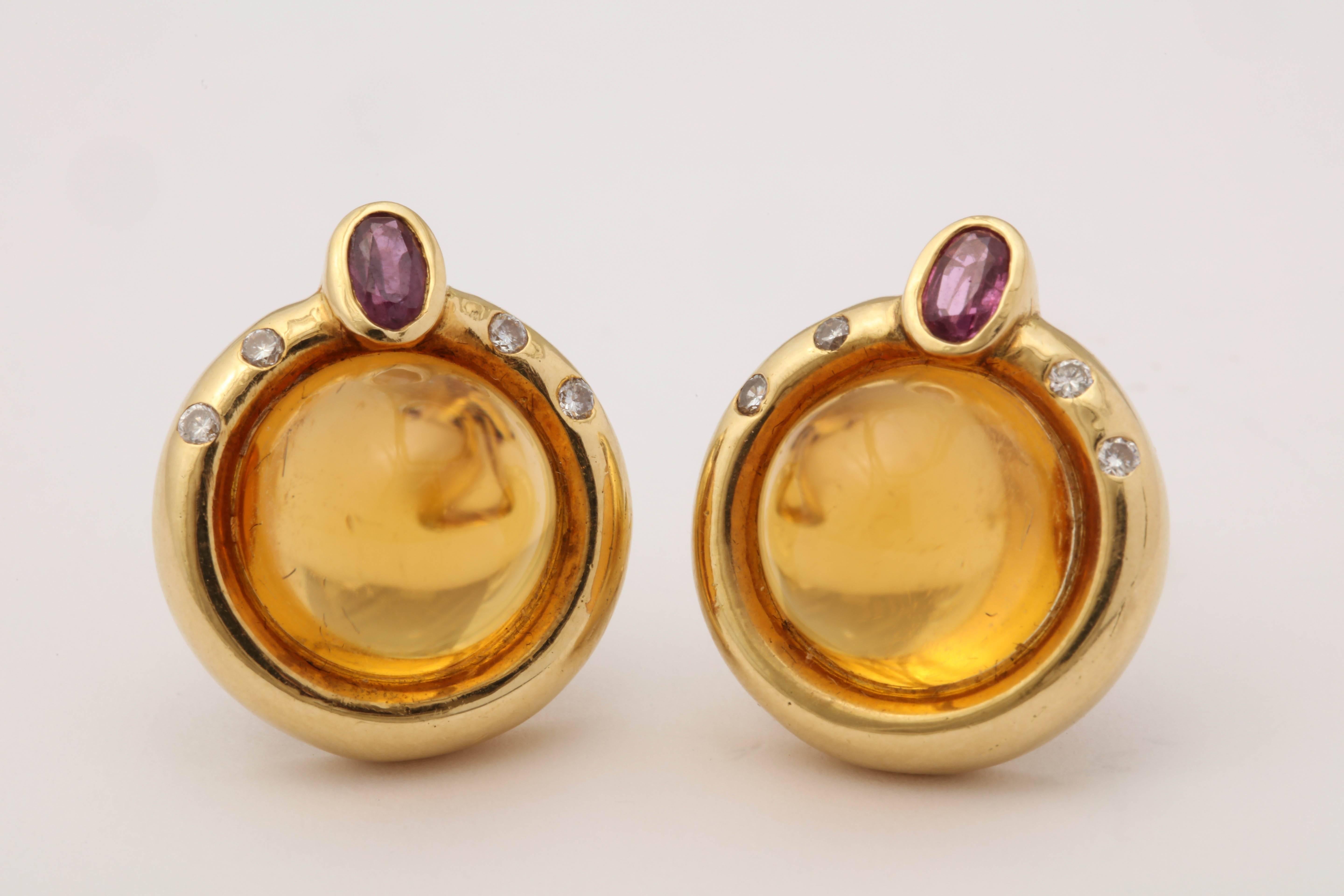 One Pair Of Ladies 18kt Yellow Gold Bezel Set Sugar Loaf Cut Cabochon Citrine Omega Back Clip On Earrings Embellished With Two Oval Cut Faceted Rubies On Top Weighing Approximately .60ct Total Weight. Further Designed With Eight Full Cut High