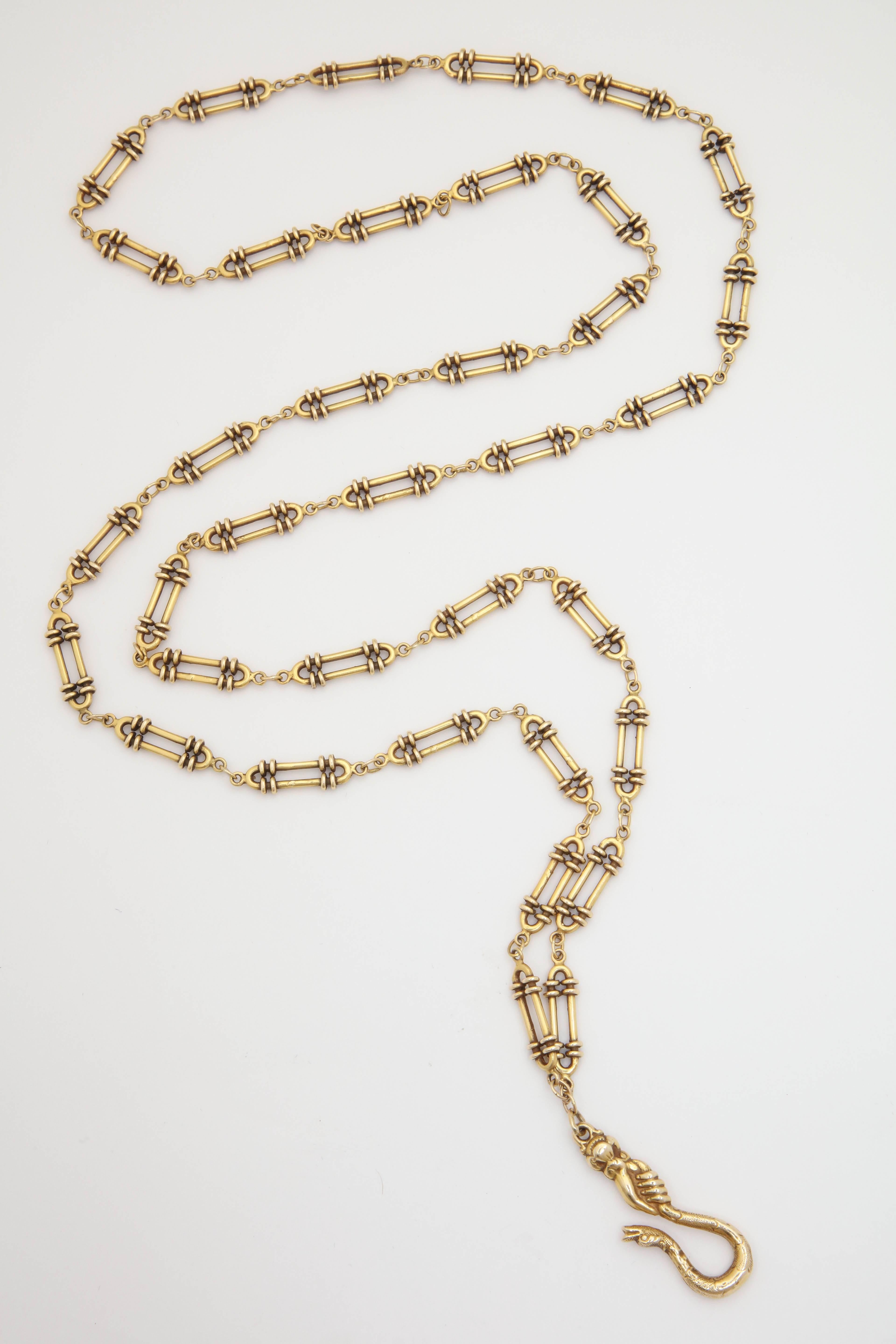 One 15ct Gold Flexible Made In England Long Oblong Link Textured Gold Chain with a Hand Crafted Unique Figural Hand Holding A Snake Clasp. Chain Measuring 40 Inches Long So You May wear It Doubled For A Shorter Look. Designed In The 1930's In England