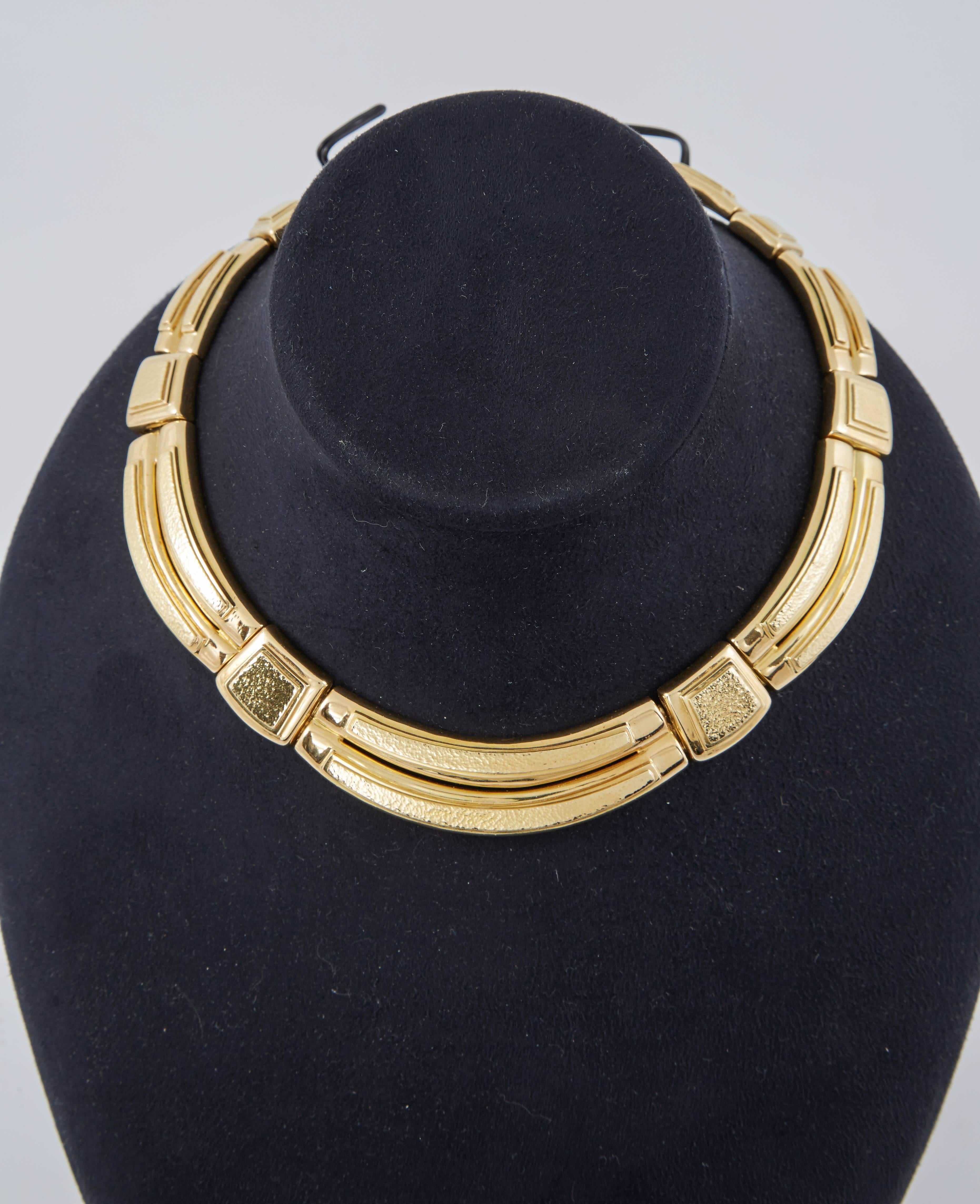Die Halskette ist ein auffälliges Kropfband aus großen Gliedern, die fein aus gehämmertem 18-karätigem Gold gefertigt sind. 