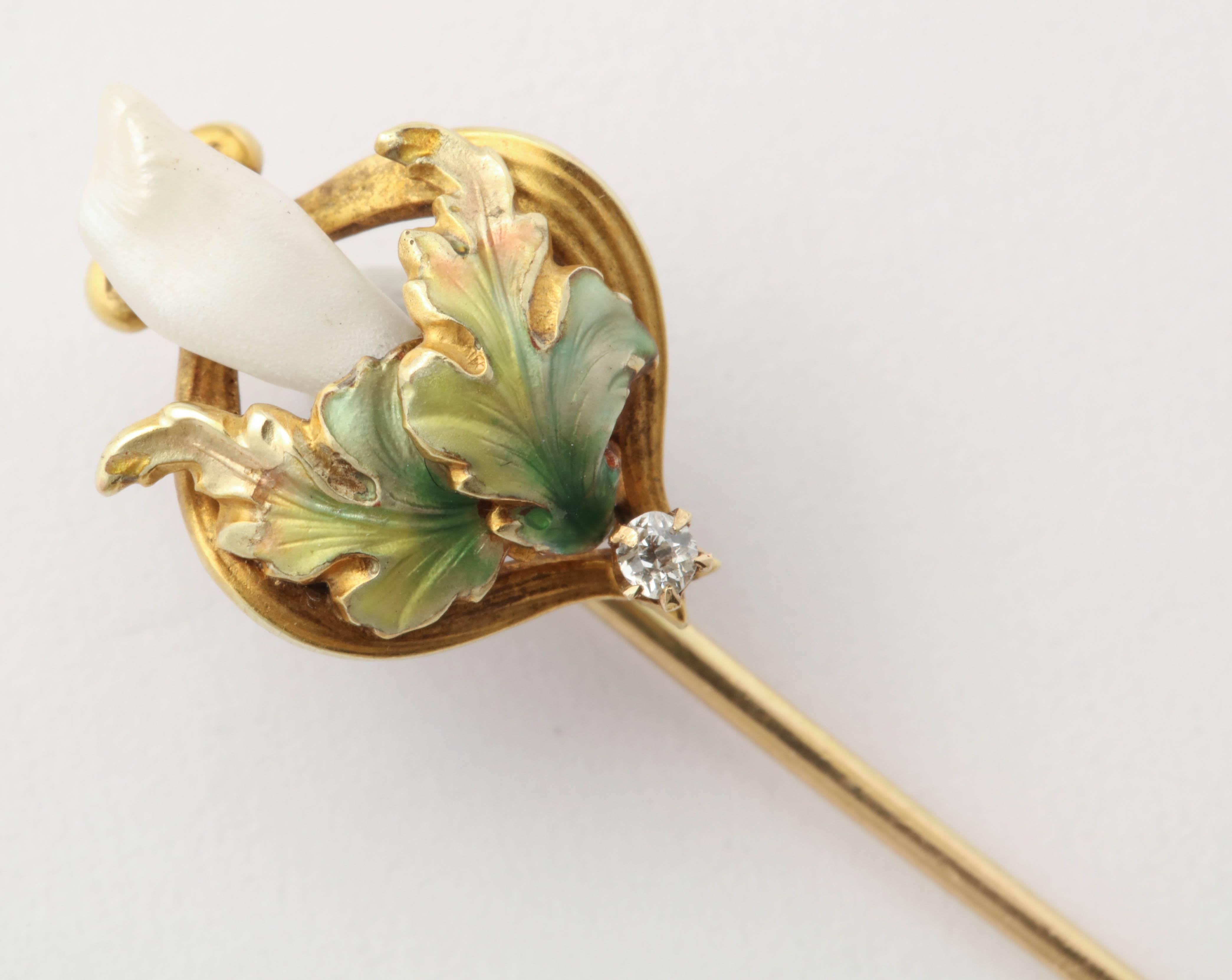 This stick pin evokes the quintessential style of the Art Nouveau period with its beautifully enameled leaves and irregular shaped pearl. A small diamond is set in the base. 14K yellow gold. 