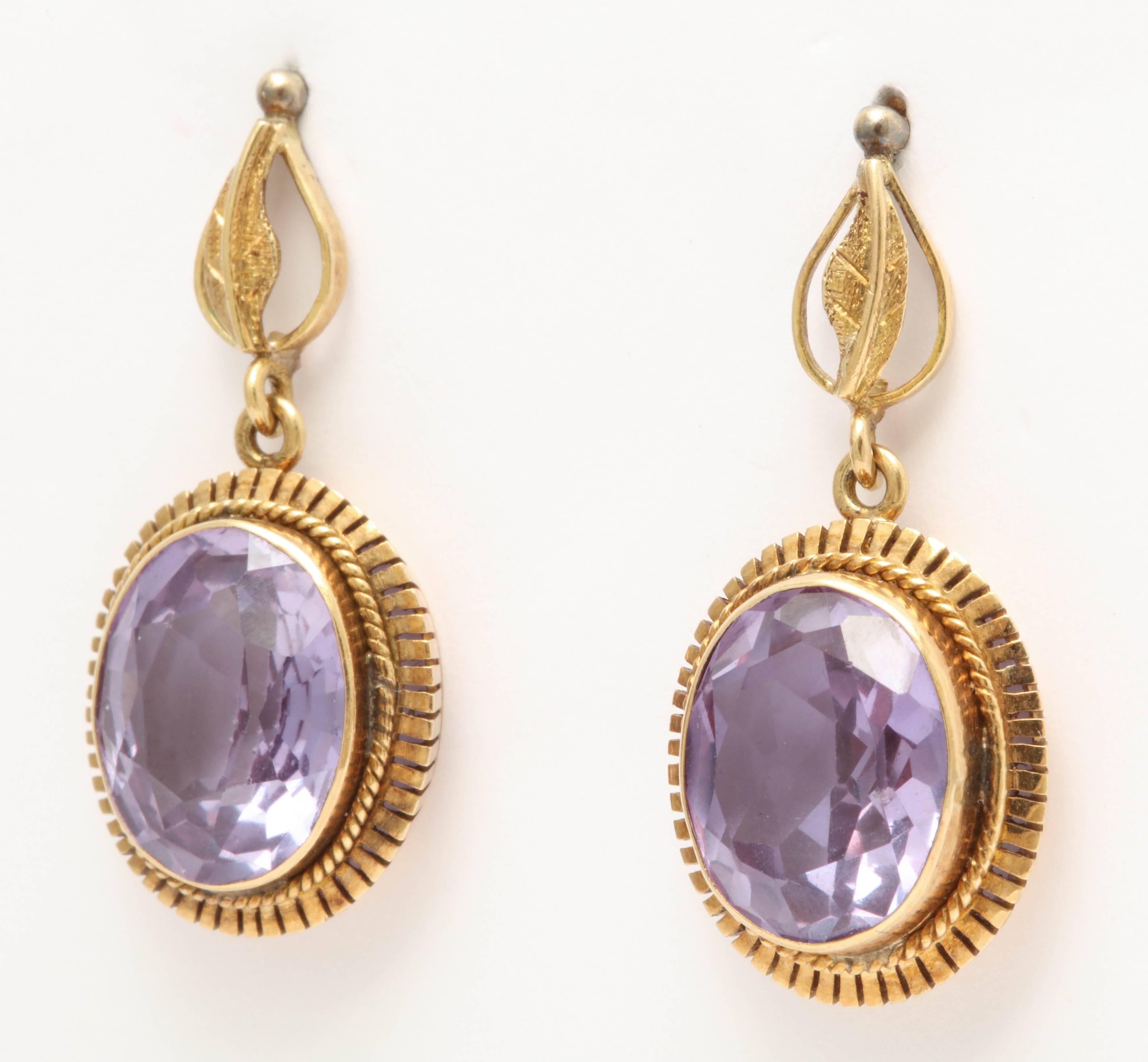 Large purple faceted sapphires are set in 18k yellow gold and dangle from a leaf designed top. Made in the 1930's, these sapphires are synthetic. The creation of synthetic sapphires is a popular and long known process starting in the 1870s. One of