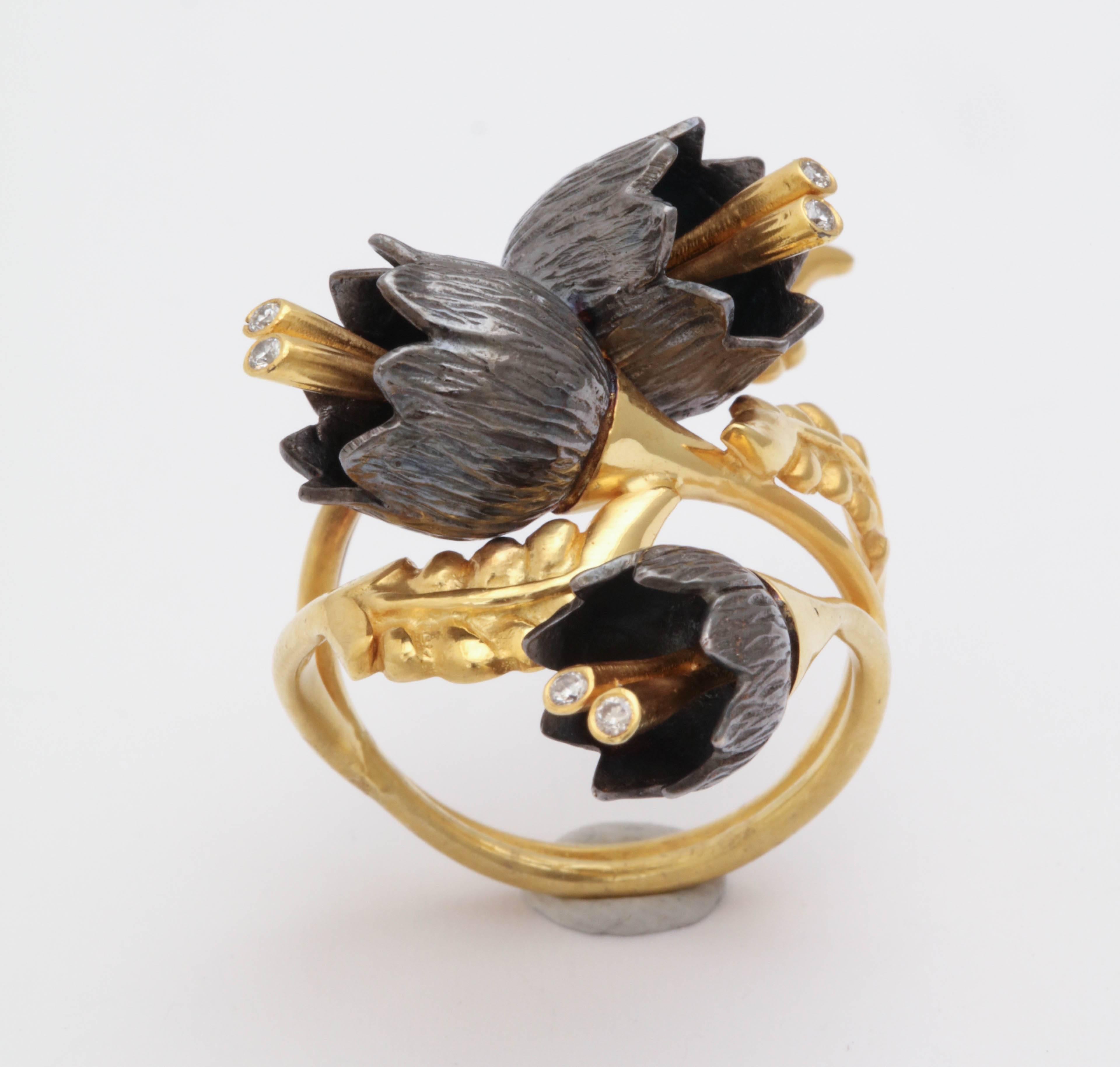 A lily of the valley ring composed of 18kt yellow gold leaves and three rhodium plated sterling silver lily of the valley flowers. The flowers cascade down an 18kt yellow gold vine. Each flower has 18kt yellow gold stamen set with diamonds. Size