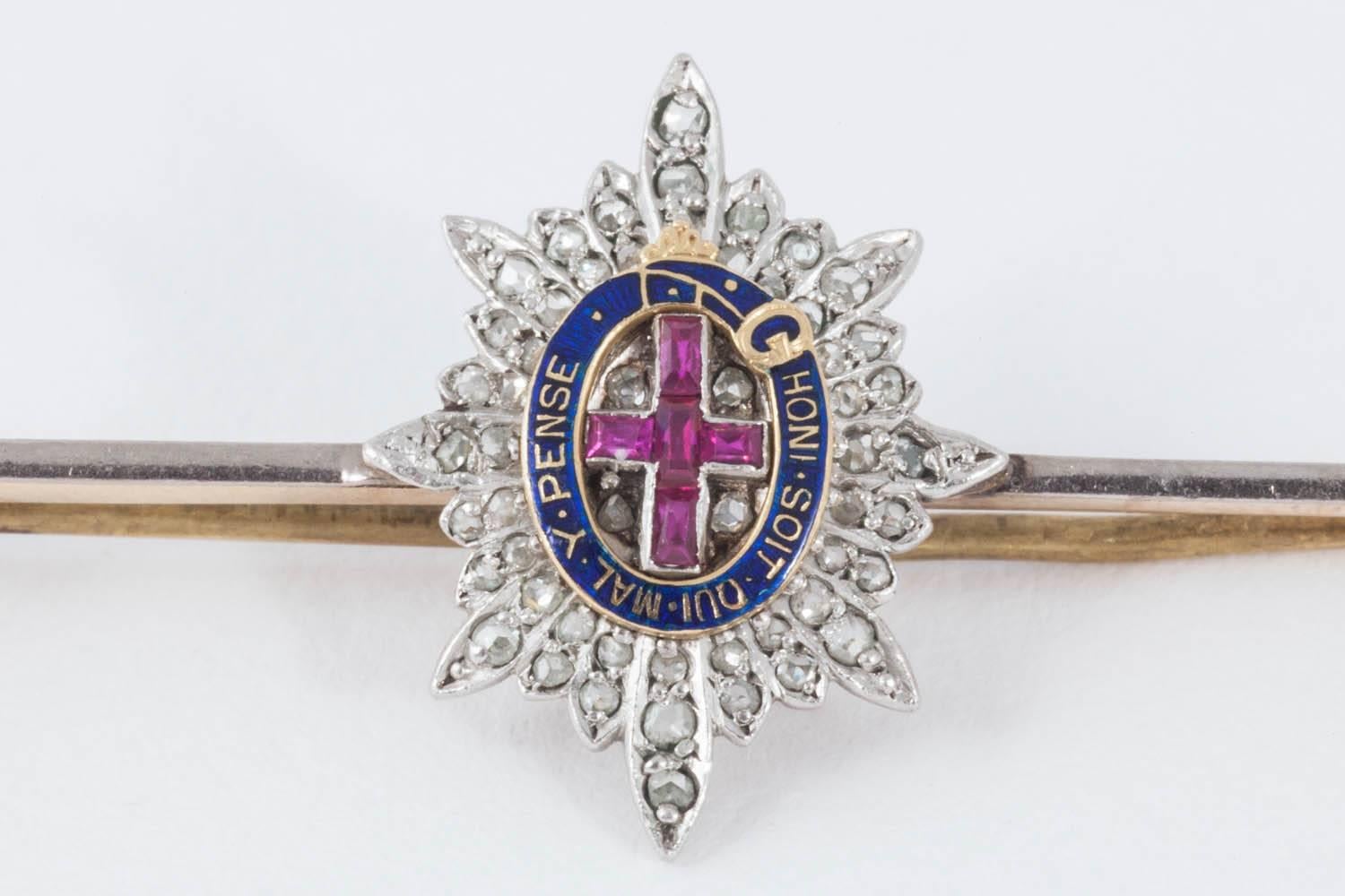 Edwardian gold bar brooch of the badge of the Coldstream Guards, platinum set with a central Burma ruby cross, rose cut diamonds and a blue enamel cartouche with the wording Honi Soit Qui Mal Y Pense.
Measures 15mm in width x 20mm in height with a