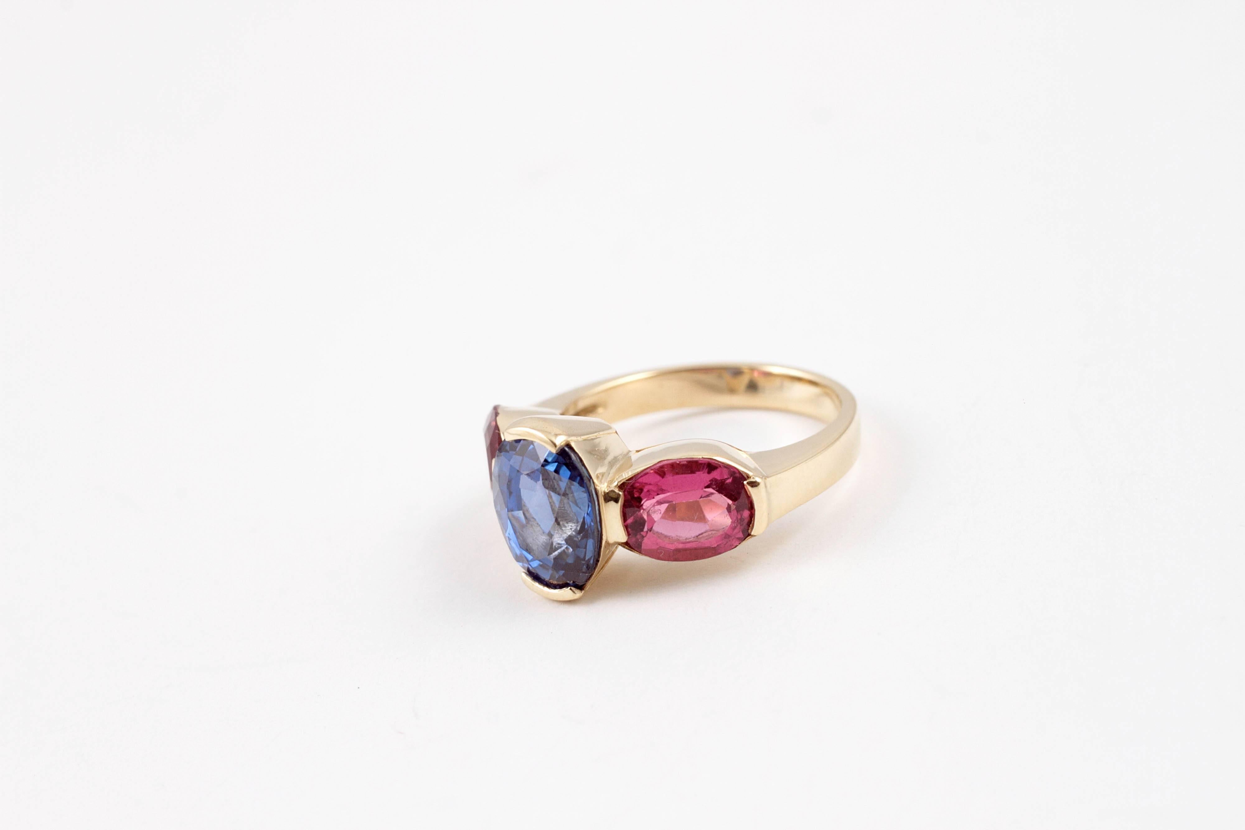 If you love bright colors - this is your ring!  In a size 5, composed of 18 karat yellow gold, the 3.00 carat blue sapphire is flanked by bright pink, oval-shaped pink tourmaline stones.  