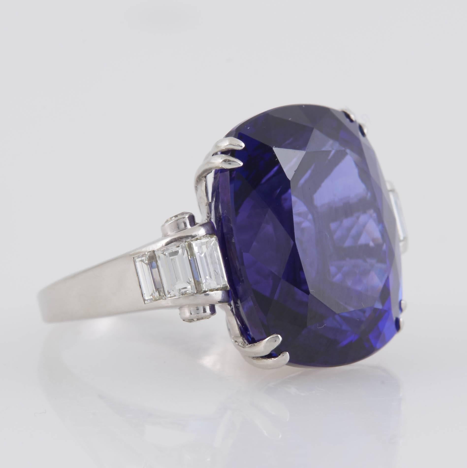 This gorgeous 34 carat cushion cut Tanzanite is set in a beautiful mounting, finely crafted in platinum, with baguette cut diamonds on each side.
