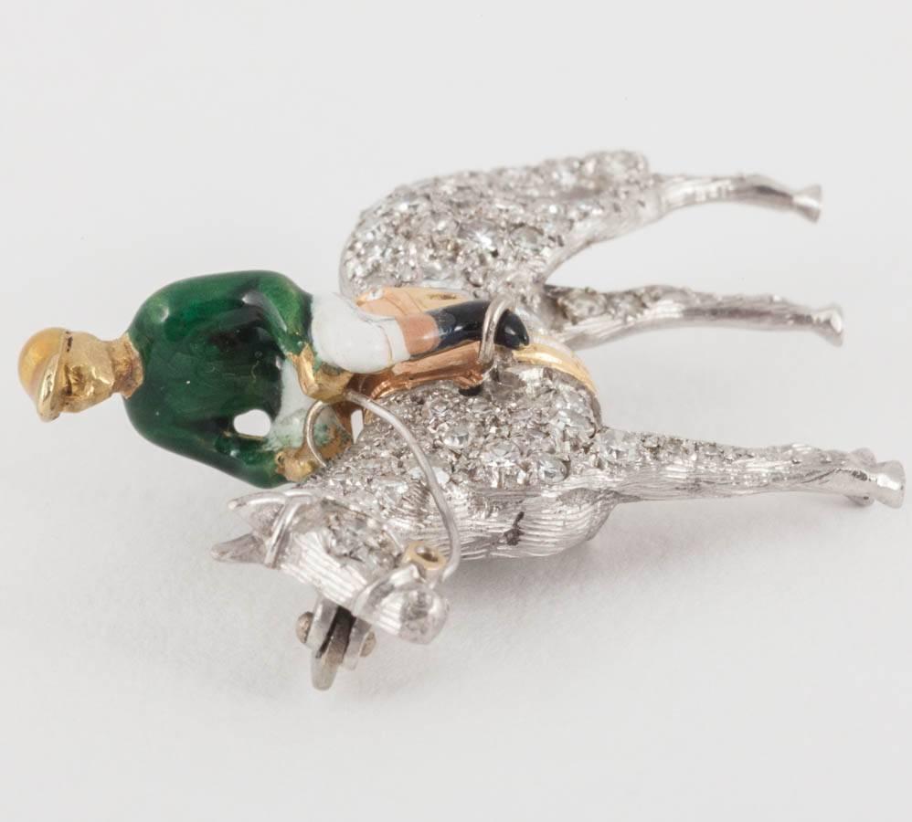 A finely made 18 carat white gold equestrian brooch in the form of a standing Racehorse. Set through with brilliant cut diamonds with the jockey in green and white enamel silks. These are normally made in the outstretched racing position but this