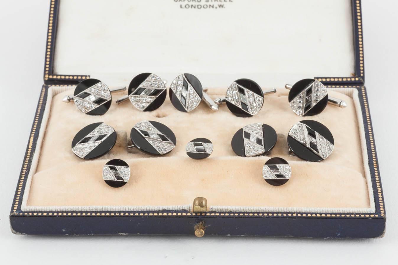 An Art Deco Gentlemen's Dress Set comprising double sided cufflinks, three studs and five buttons. Mounted in platinum with onyx, diagonal lines of diamonds and a central baguette cut diamond. French marks.
Measures 13mm across (cufflink).
Early