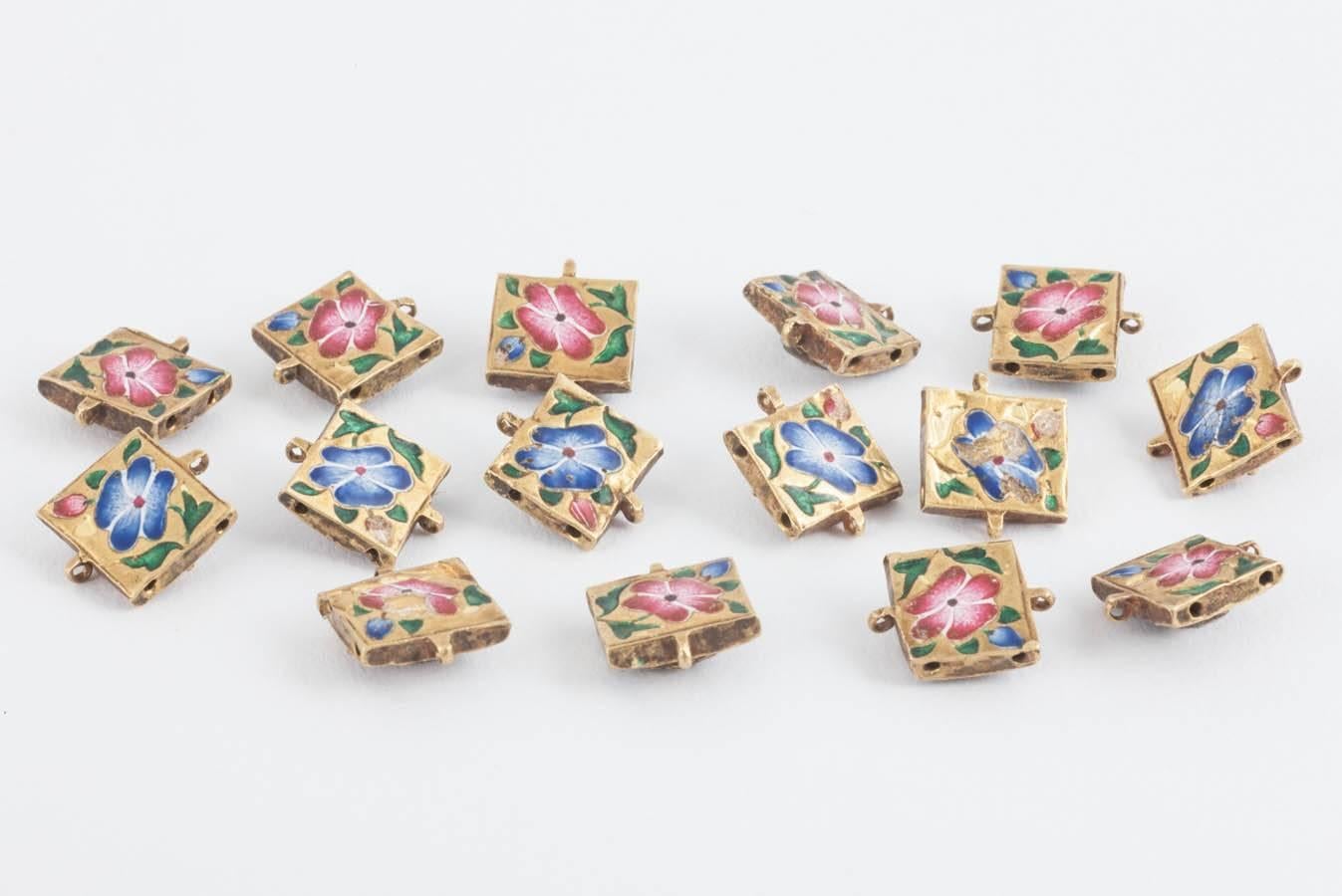 Fifteen,Indian plaques made in the 18th century,originally strung together as a bracelet,all with coloured enamel floral design,the fronts set with either a rose cut diamond,or a cabochon Burma ruby.c,1785