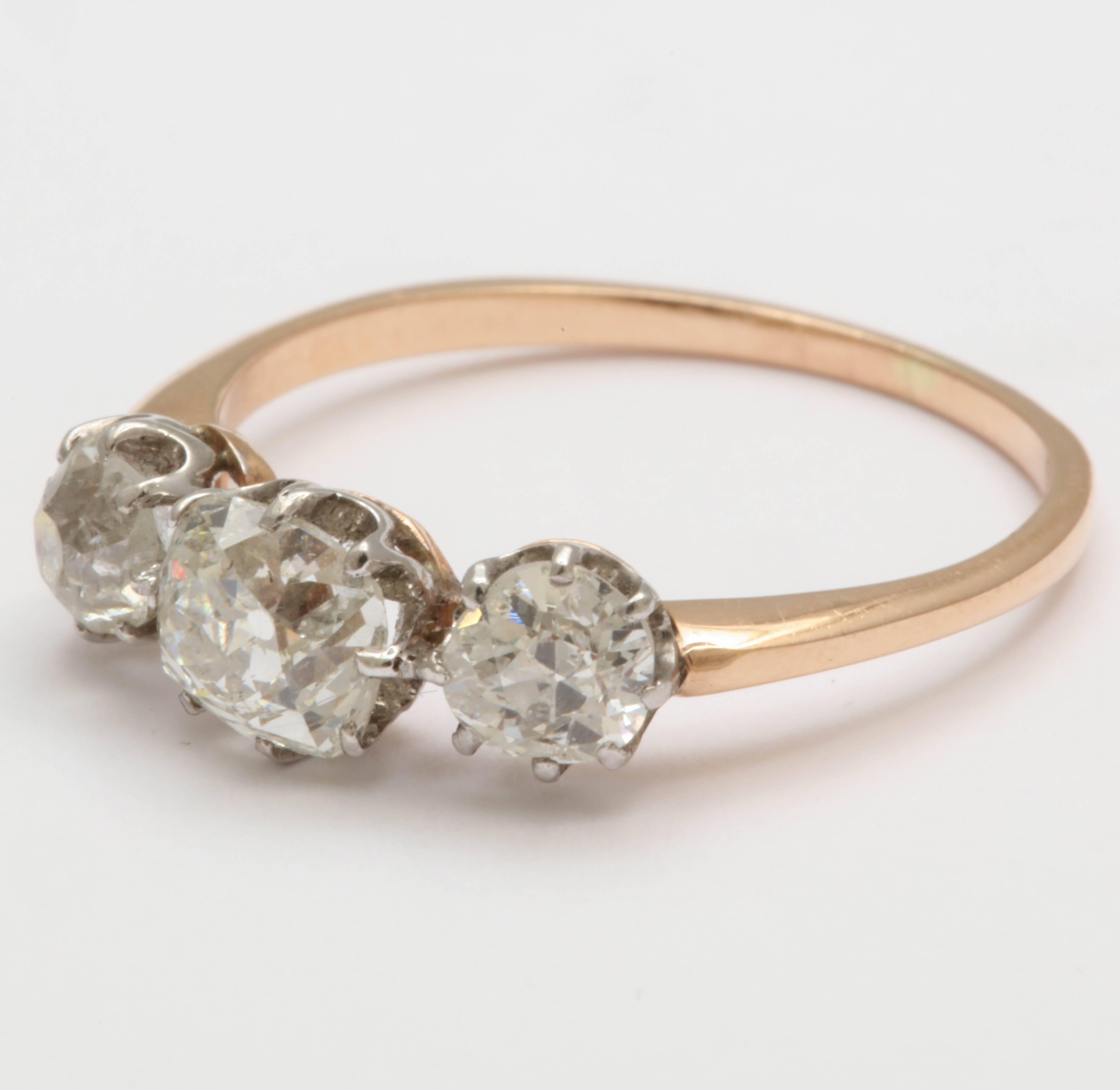 Three old mine cut diamonds are set in silver in an open back prong setting over a rosey-yellow gold. The center stone is approximately .72cts and the side stones approximately .66cts total. Made in the late Victorian era. 