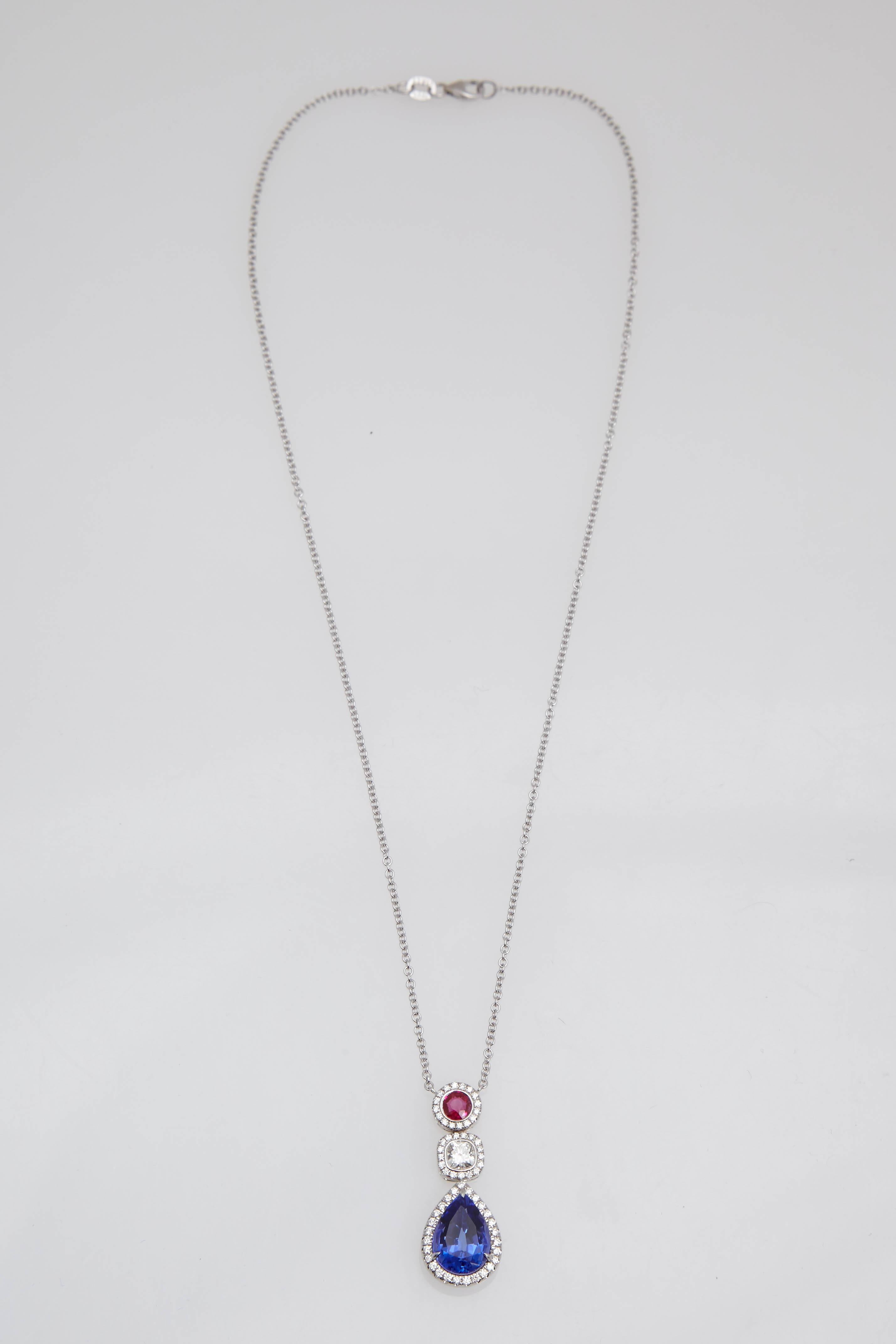 18 Karat white gold tanzanite, diamond, and ruby necklace consisting of 4.36 carat pear shaped tanzanite, 0.37 carat cushion shaped diamond, and a 0.37 carat round Burmese ruby enhanced by 57 round brilliant cut diamonds weighing 0.44 carat. The
