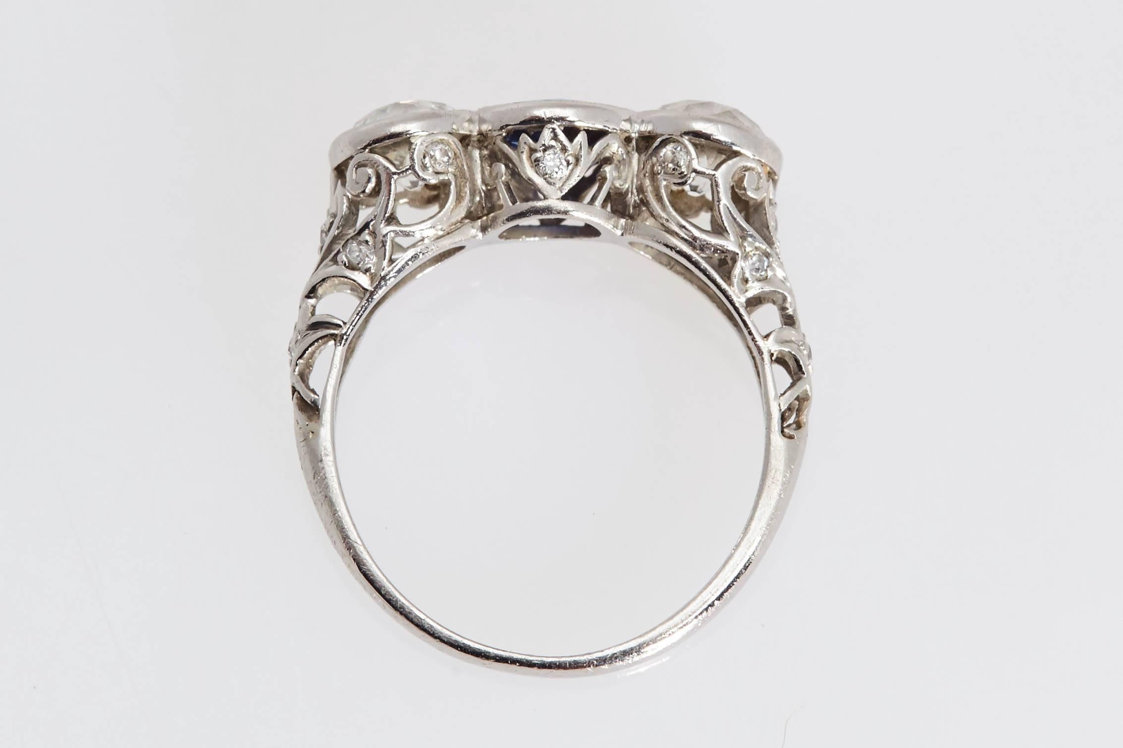 Beautifully detailed Edwardian platinum ring.  The ring is made up of a round blue sapphire in the center weighing .78 carat and two old miner shaped diamonds weighing approximately 1.60 carats. The diamonds are 