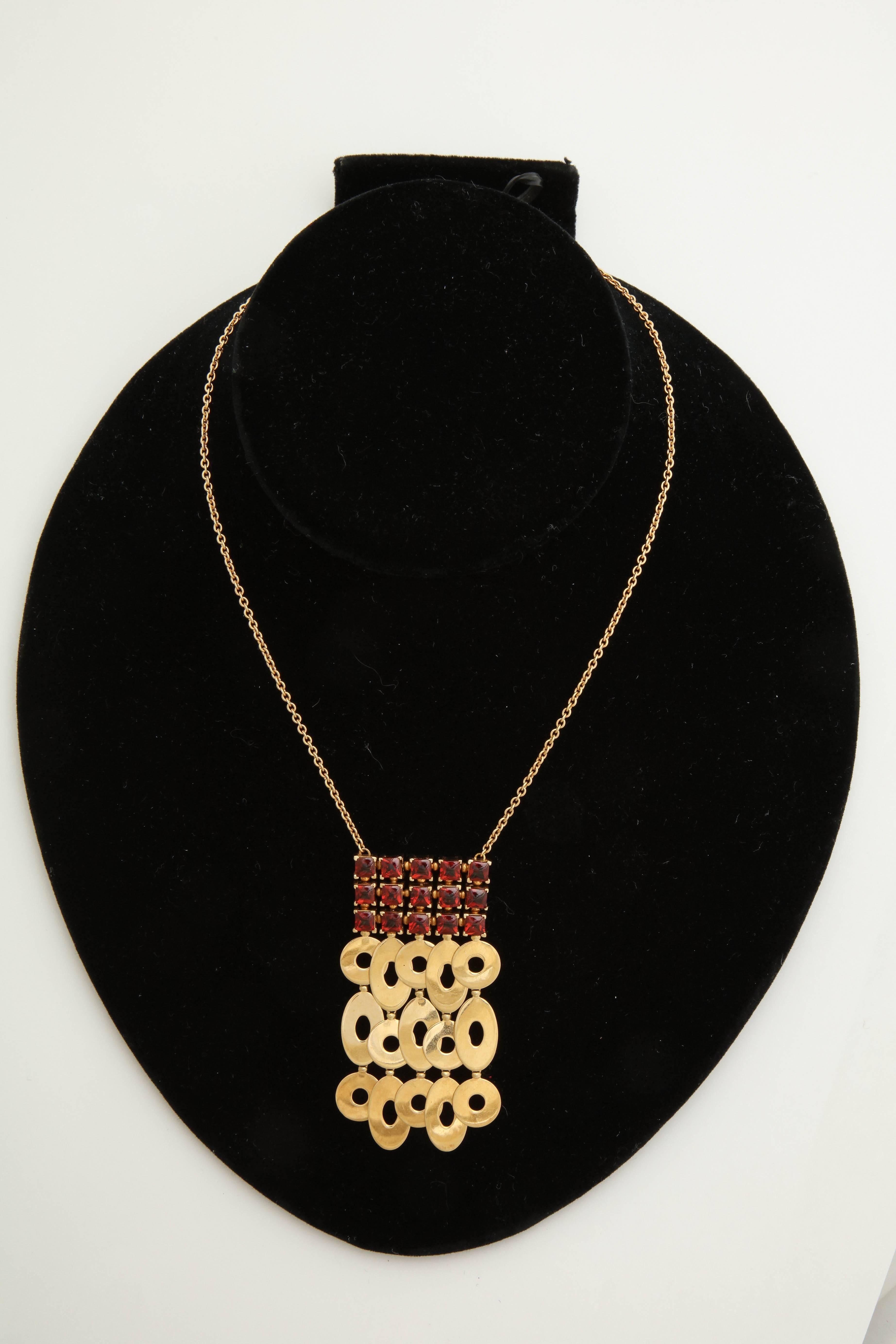 One Ladies Pendant Style Necklace Composed Of 18kt Yellow Gold And Embellished With Fifteen Buff Cut Sugarloaf Cut Prong Set Garnet Stones Weighing approximately 3.0 carats. Necklace Is Further Designed with Fifteen Asymmetrical Open Discs Of Oblong