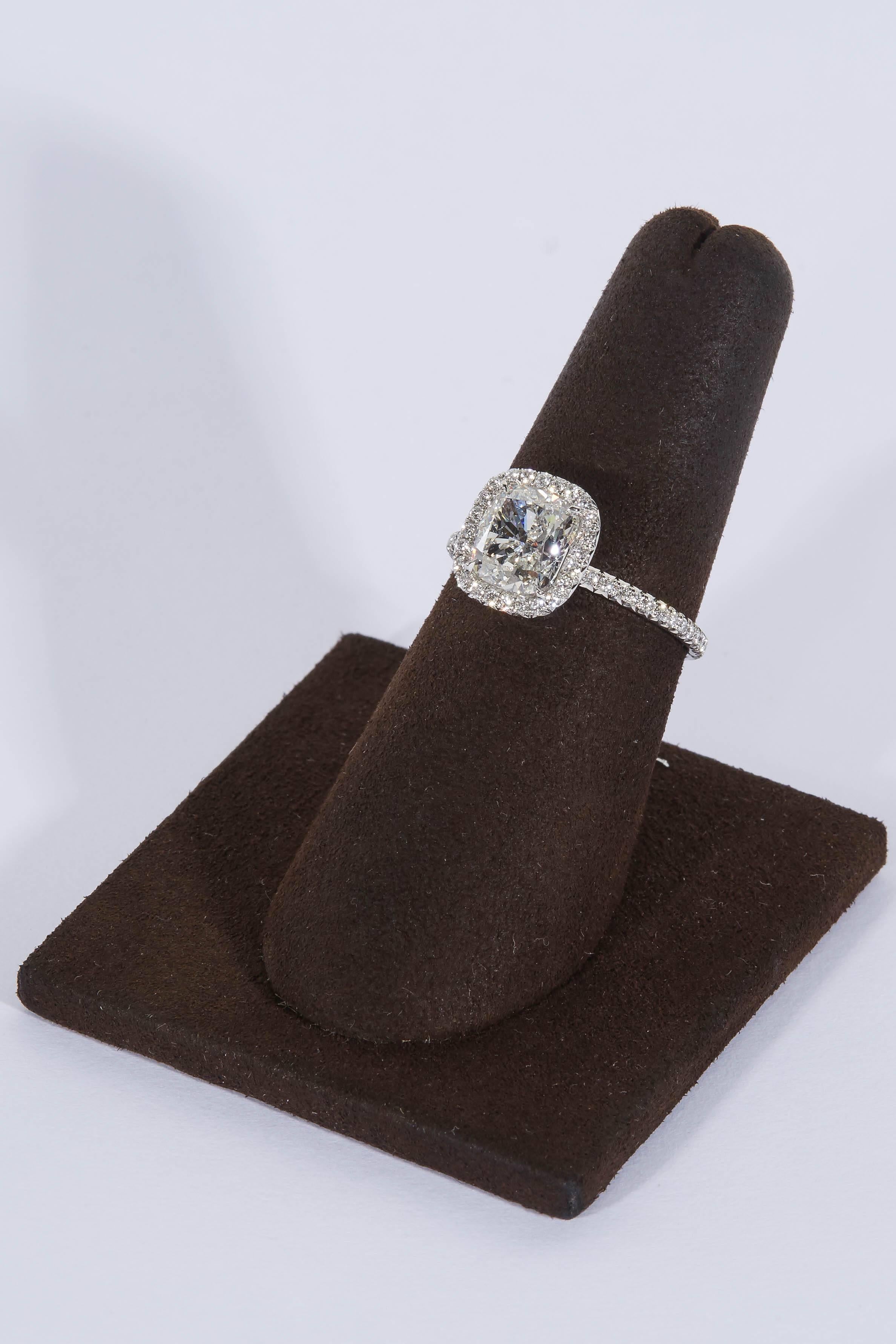 
A hand crafted delicate diamond halo mounting with a fabulous 2.04 carat center diamond.

2.04 carat H color SI1 GIA certified cushion cut diamond

.50 cts of round brilliant cut diamonds

Platinum

Currently a size 6 but can be resized,
