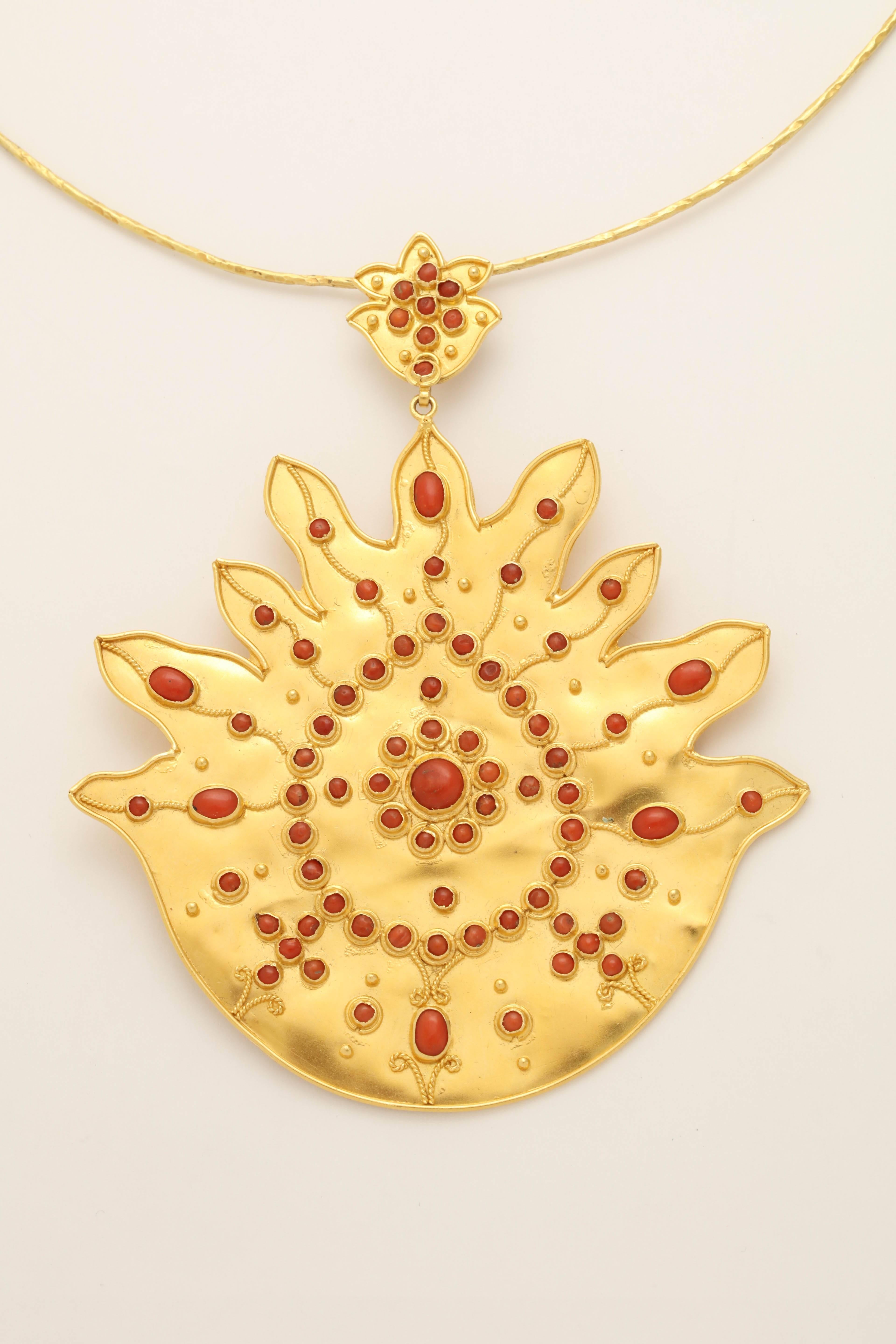 An 18kt yellow gold flame pendant with an 18kt yellow gold wire necklace . The pendant is decorated with 18kt yellow gold rope, granulation and bezel set oval and round cabochon coral beads.

Pendant length: 4.15 inches
Pendant width: 3.35