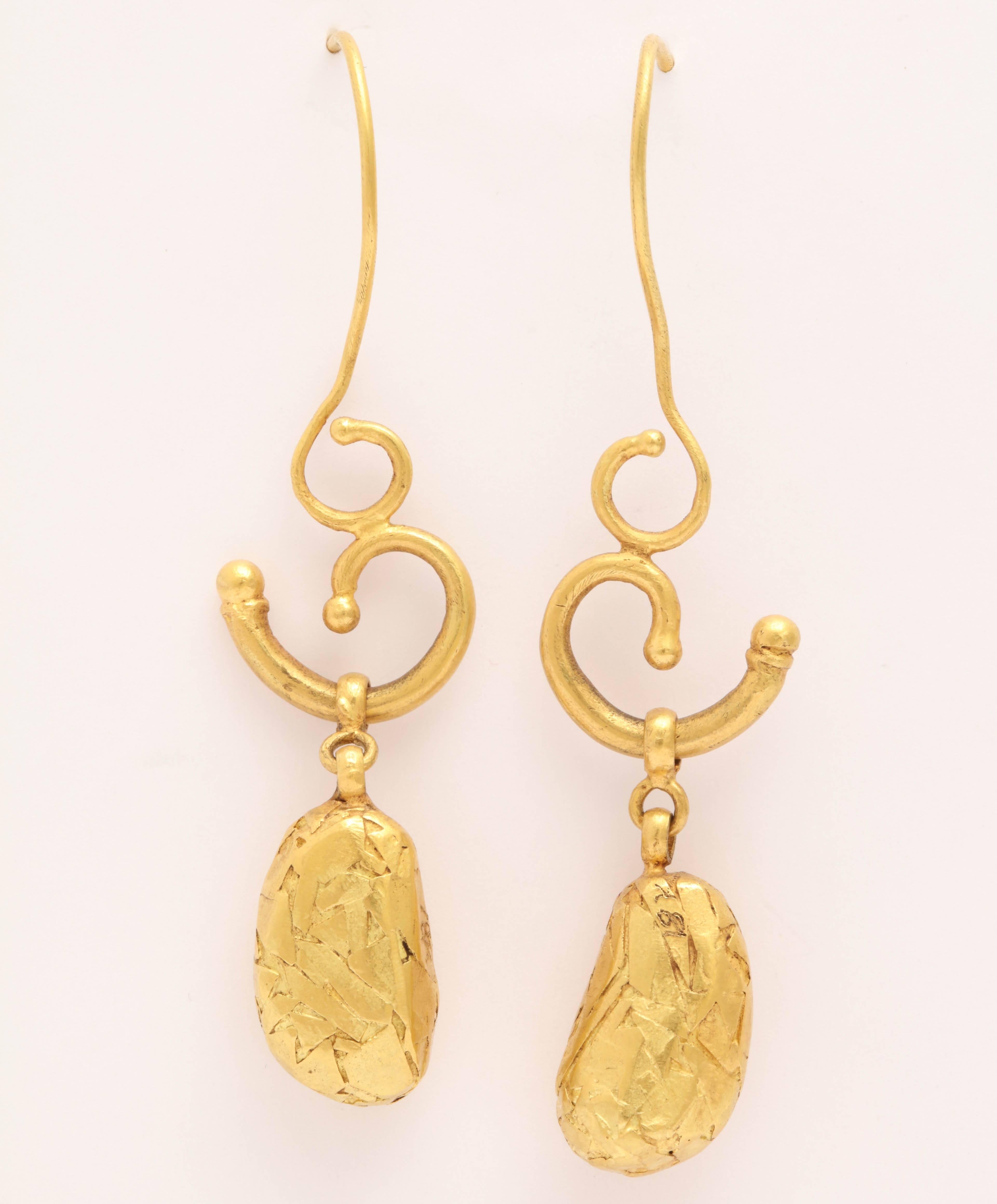 A pair of 18kt yellow gold pebble earrings. Each ear wire is attached to a cornucopia which suspends a gold textured pebble bead.

Length: 2.50 inches
Width: .60 inch