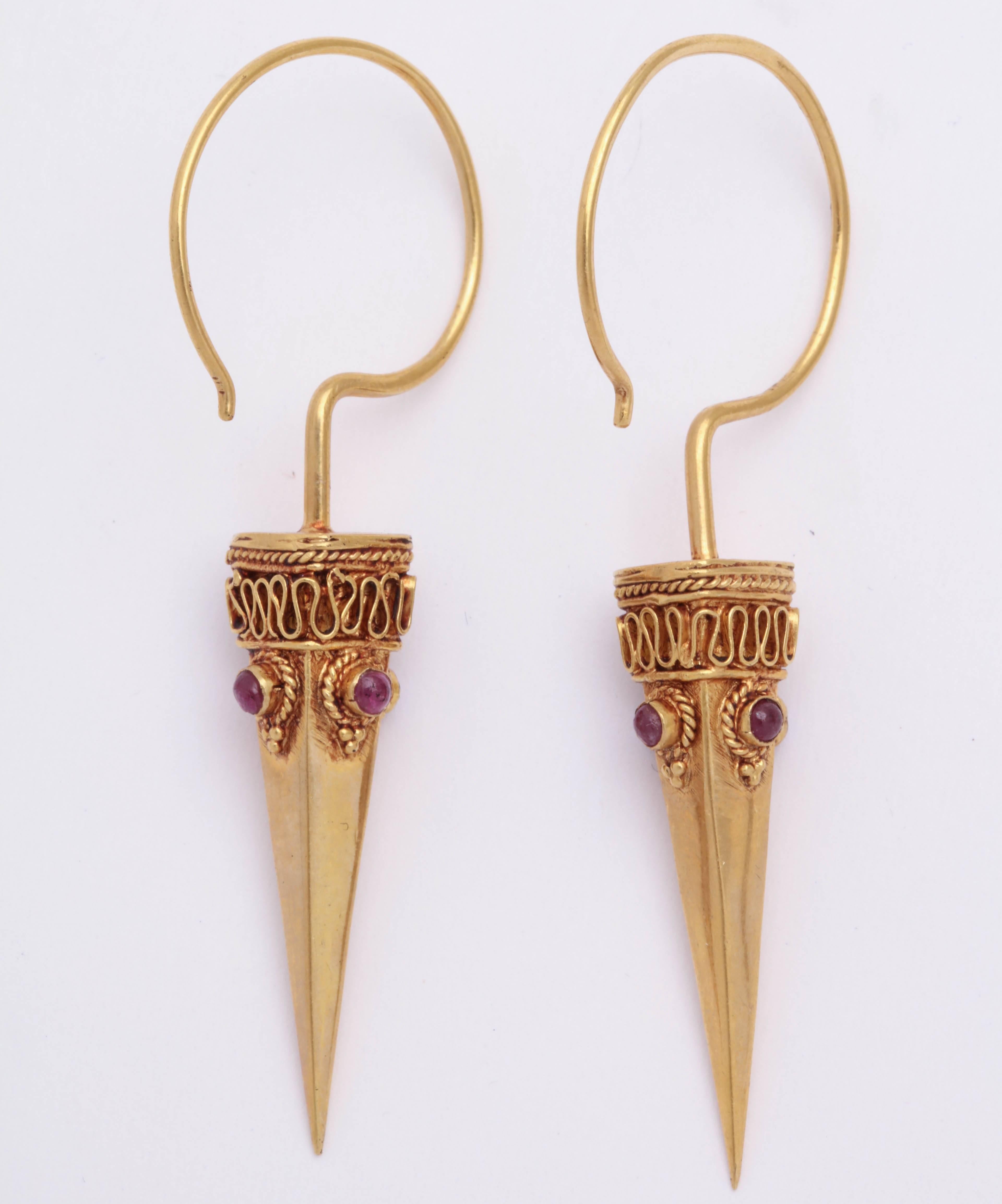A pair of 18kt yellow gold and cabochon ruby spike earrings. The earrings are suspended from large 18kt yellow gold ear wires. The rubies are bezel set and framed with granulation and rope.

Length: 2.25 inches
Width: .30 inch