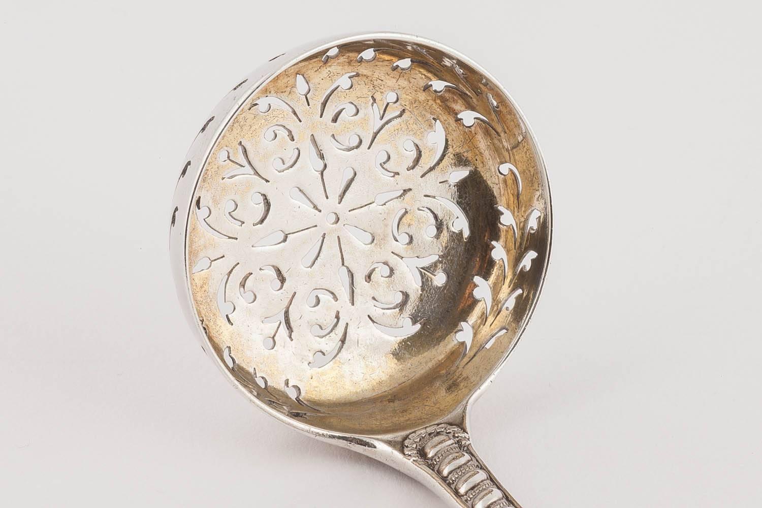 A beautiful pairing: the sterling silver spoon with a gilded interior pierced with a decorative foliate design, with pair of sugar tongs, en suite, Napier Pattern.

By George Adams, London 1864, hallmarked. Monogrammed

The spoon: 6 in. (15.2 cm.)