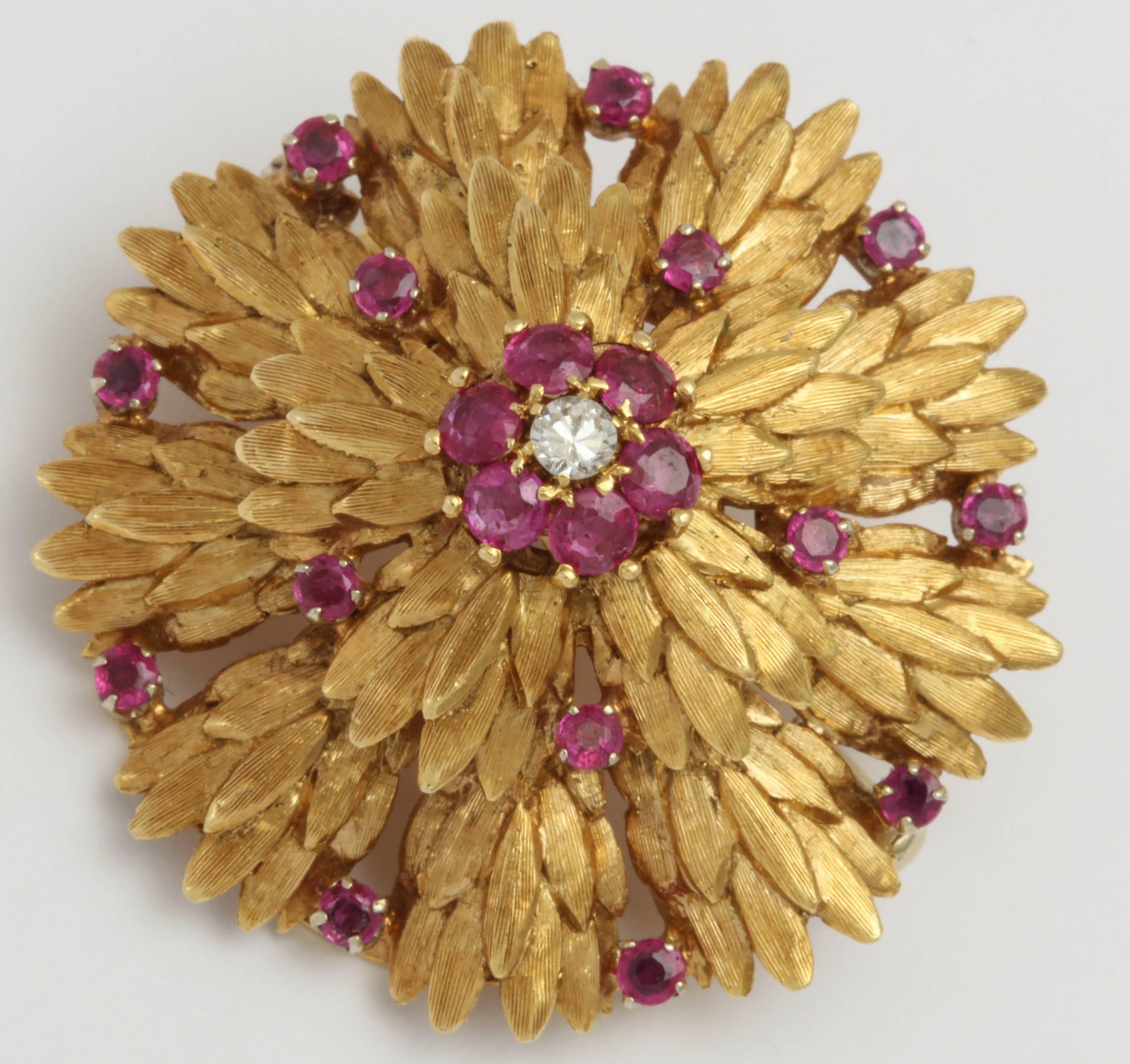 Circular three Dimensional chased 18kt Yellow  Gold Pin set with vivid faceted Rubies and centered with a full cut Diamond surrounded by 6 Rubies. Marked 18kt Italy.  Very chic and very elegant hearkening an age of Suits , White Gloves and a Pillbox