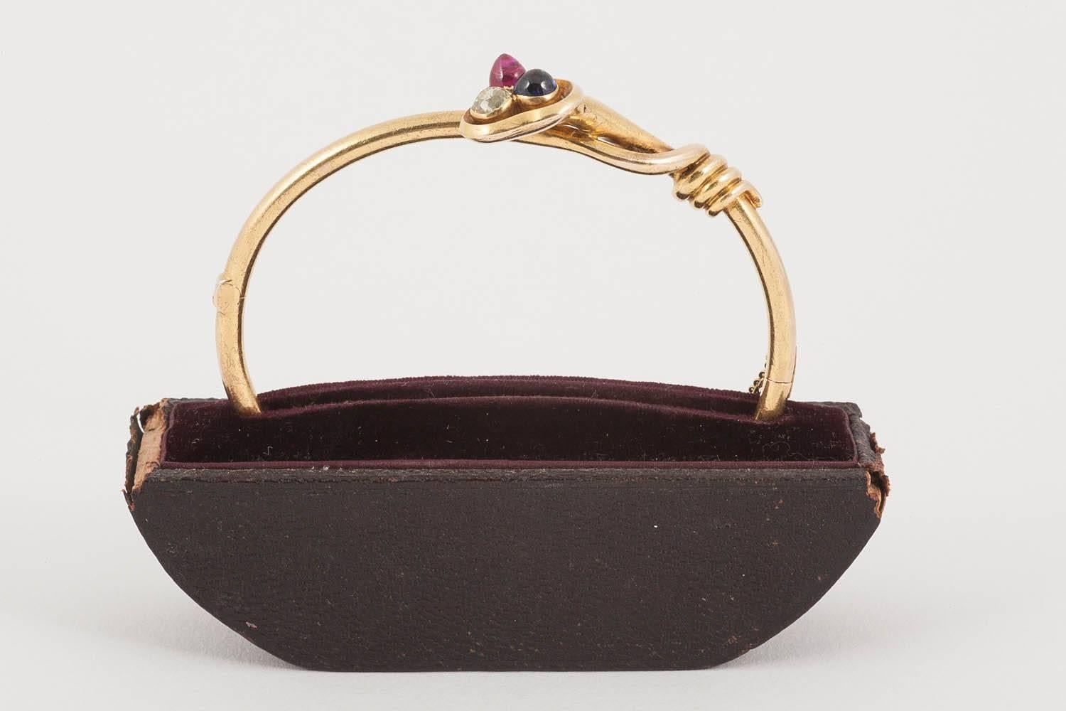 Late Victorian 18 carat gold tubular antique bangle of cross over design in the Russian style. Set with a central old cushion cut diamond, a fine coloured cabochon cut sapphire and a Burma ruby in excellent condition and of fine colour. Hinged