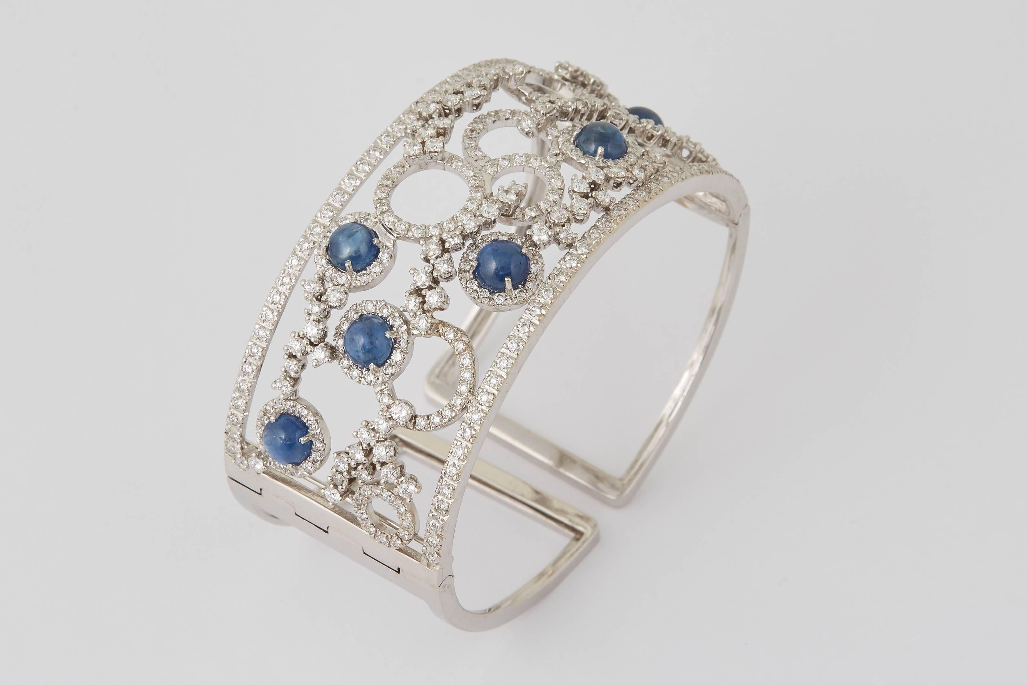 
A unique beautiful design.

9.11 carats of cabochon blue sapphires, 5.90 carats of white round brilliant cut diamonds. 

18k white gold 

Approximately 1.35 inches wide. 

Made in Italy