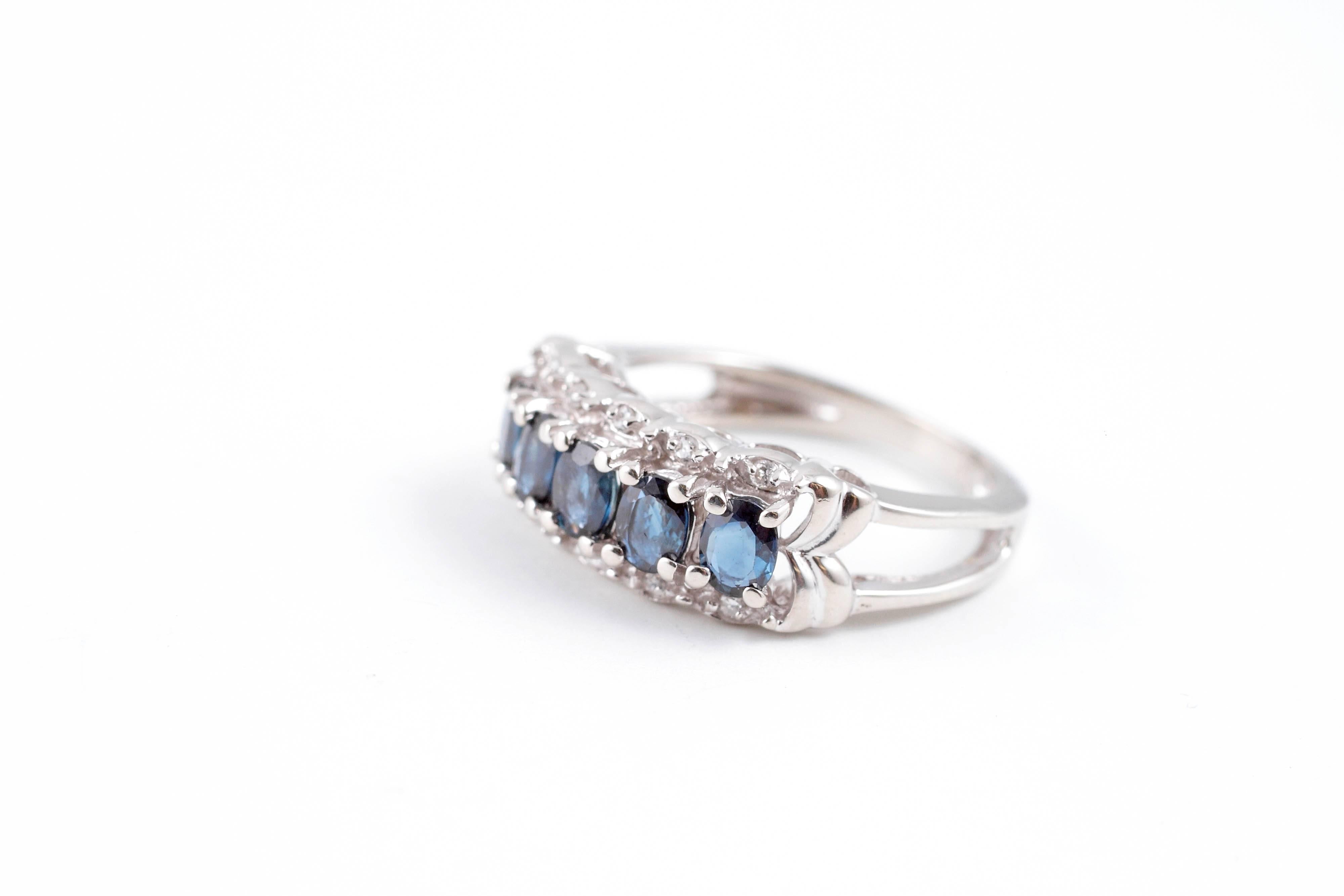 Either hand would love to have this ring on it!  It is in 18 karat white gold and features a center row of oval-shaped, blue sapphires, flanked on either side by a row of diamonds!  Size 5 1/2