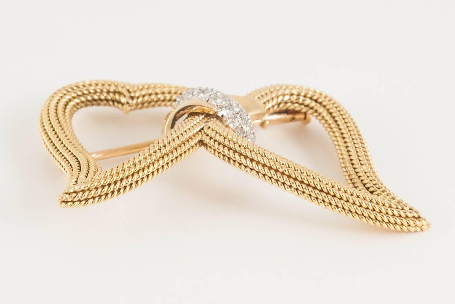 A finely made 18kt yellow gold brooch in the form of a double heart,tied with a gold and diamond set knot,signed Sterle of Paris,of heavy quality,c,1950