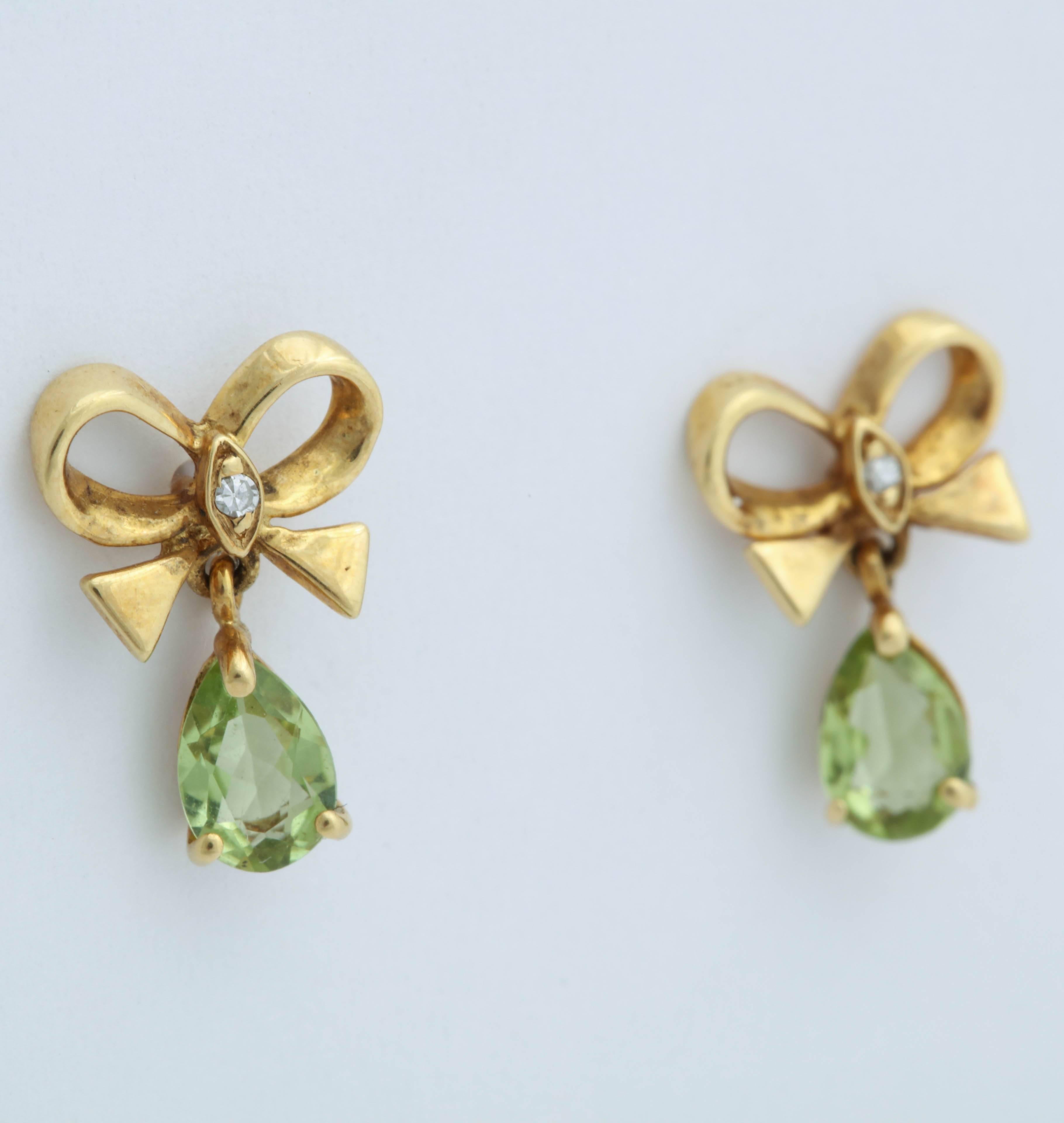 These are sweet 14 kt yellow gold bow earrings with a central diamond and a dangling pear shaped peridot.  The peridots are 5 X 7 mm and can be ordered with an amethyst or a citrine instead of the peridot.