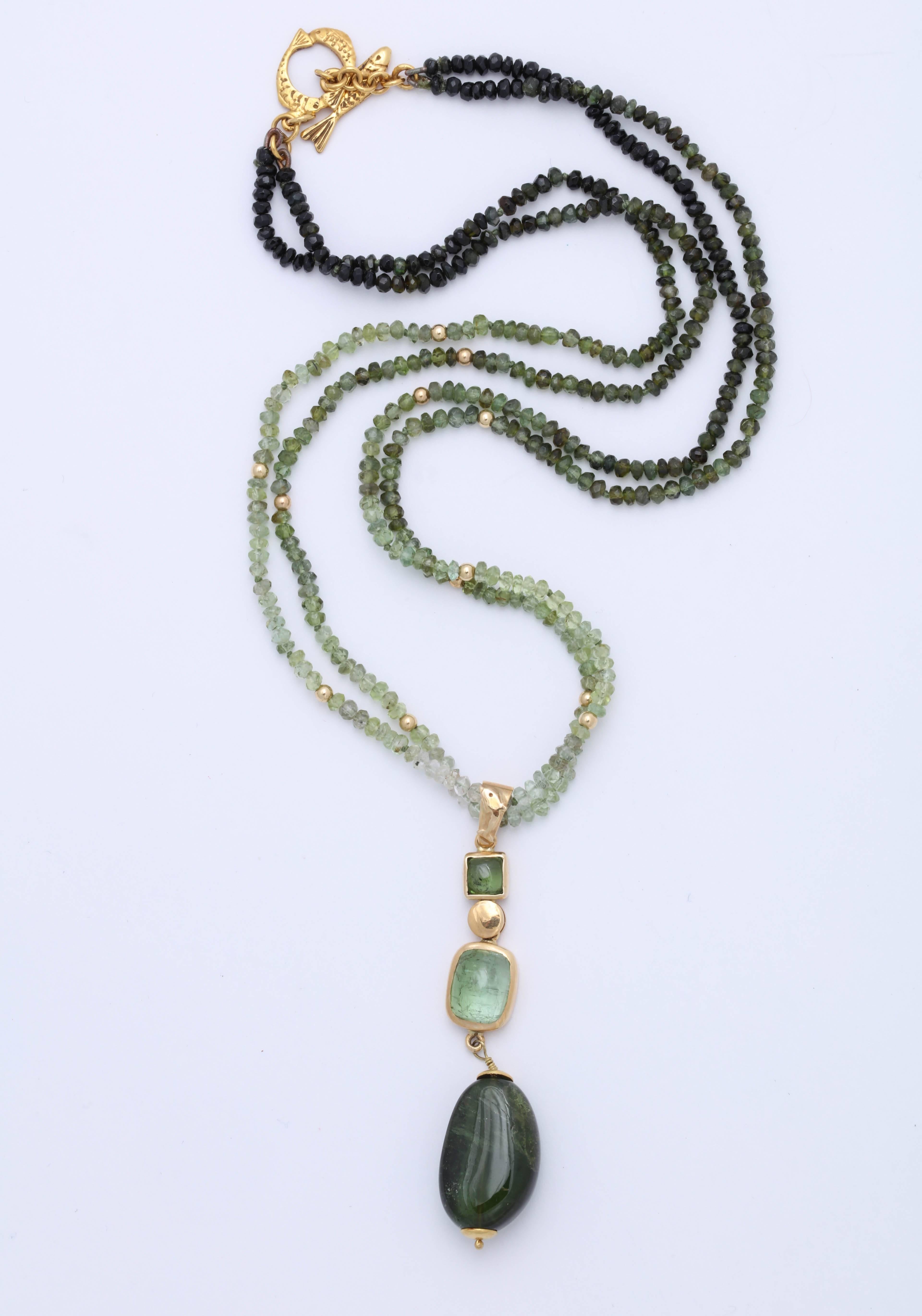 These beautiful ombre shaded green tourmaline beads suspend a 3 part pendant with square and rectangular cabochon cut green tourmalines in gold bezel settings. The bail is enhanced with a lovely gold dolphin. The necklace is finished with a toggle