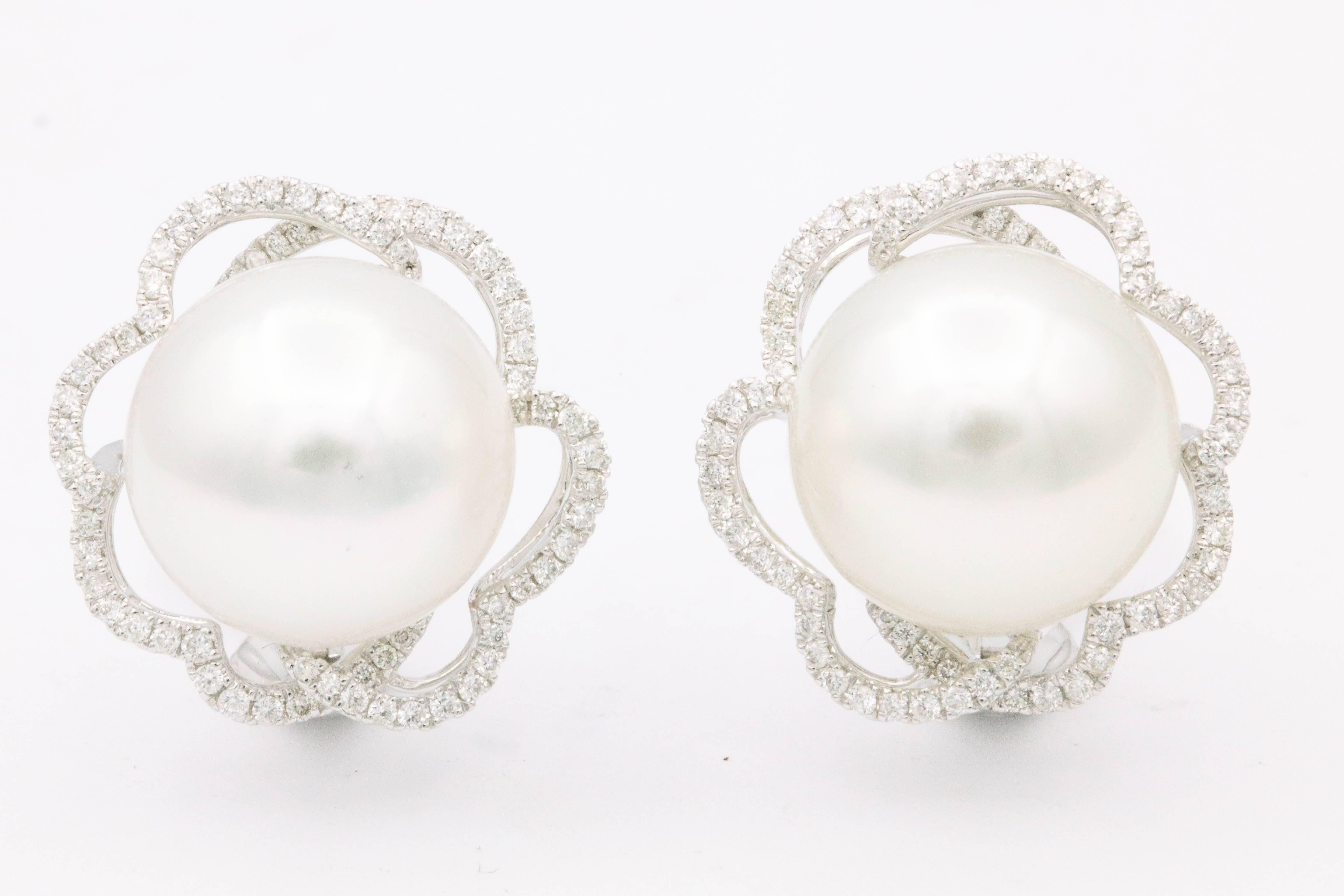 18K White gold earrings featuring two South Sea Pearls measuring 13-14 mm flanked with a diamond floral halo weighing 0.60 carats. Color G-H Clarity SI