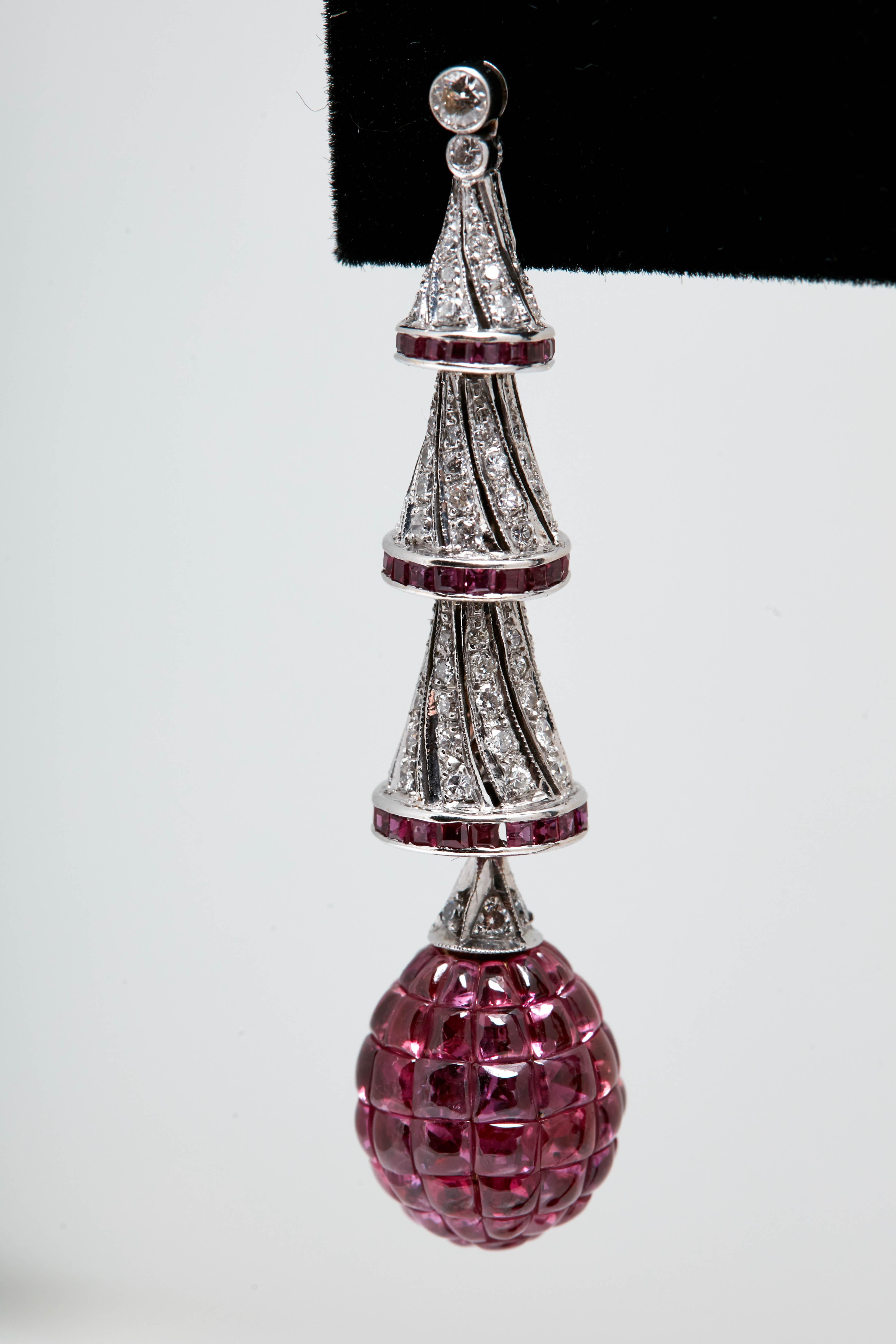 A pair of pendant earrings in 18kt white gold with invisible set red rubies and diamonds. Circa 1980