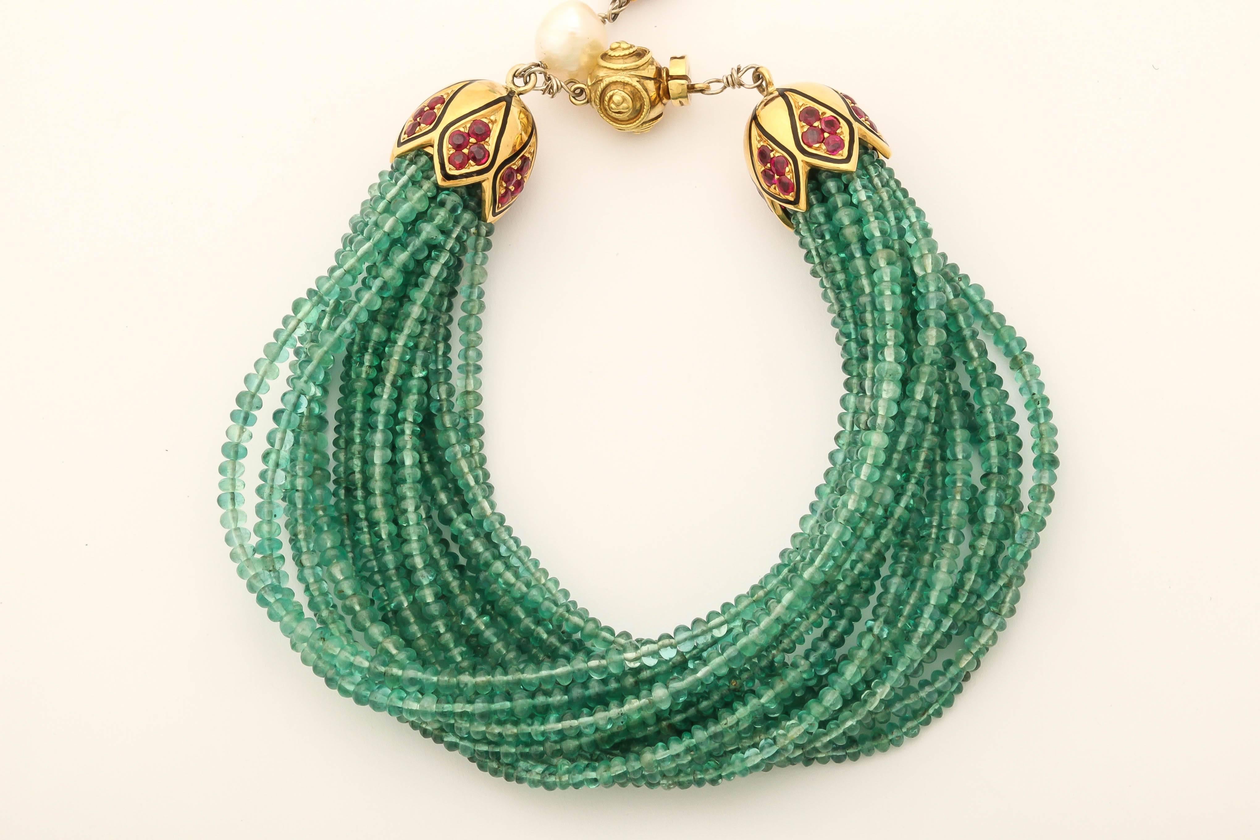 This bracelet has 17 stands and approximately 400 cts of 3 mm beautiful green emerald beads. The clasp is 18 kt yellow gold with 2.78 cts faceted rubies, black enamel. The 'tail' hanging from the clasp is made of fresh water pearls a large oval ruby