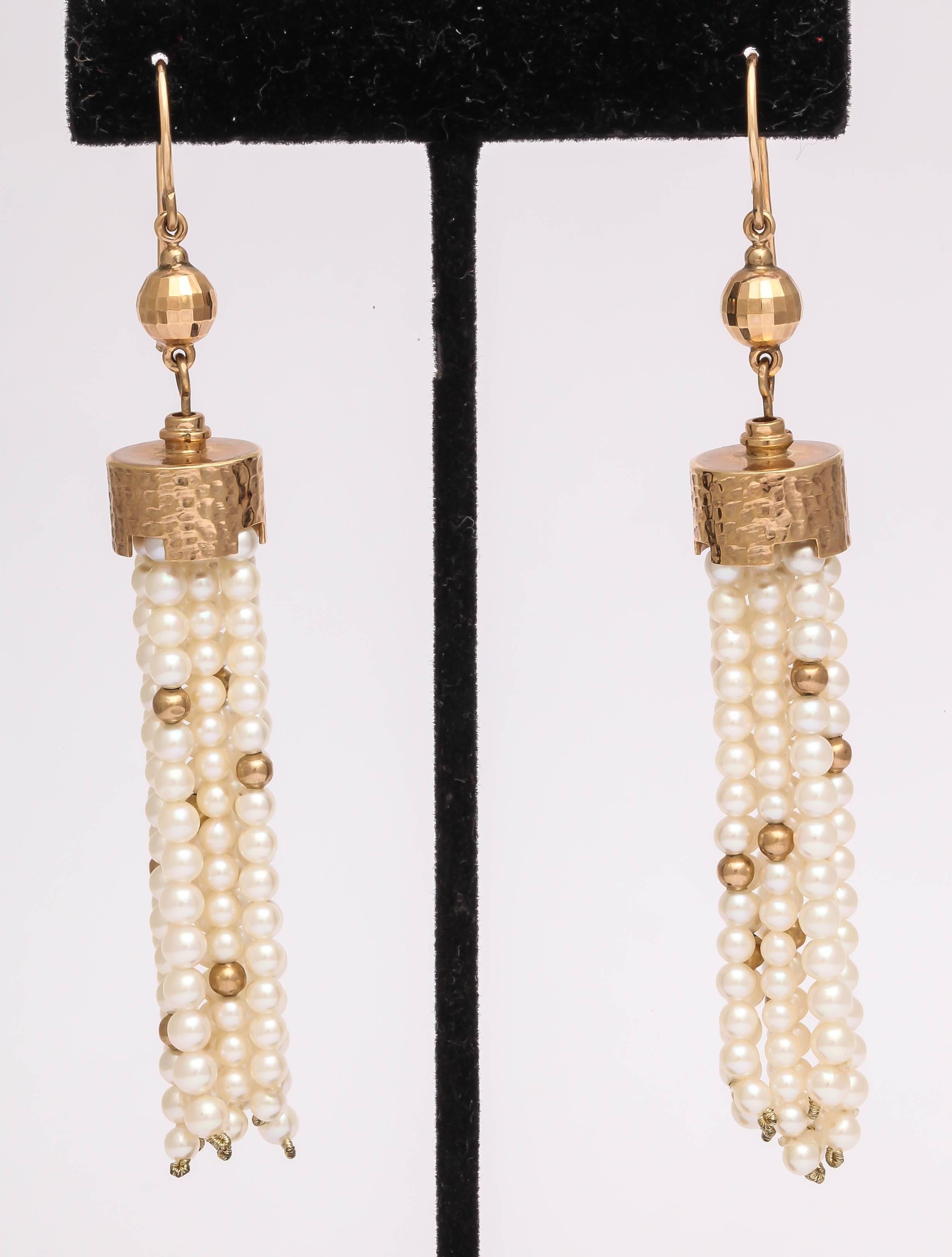 Long and elegant 14 kt pearl and gold bead tassel earrings. The extra long ear hook is comfortable and more secure. the hook and tassel are connected by a faceted gold bead, for sparkle and the cap hammered gold with turret like cut outs. The total