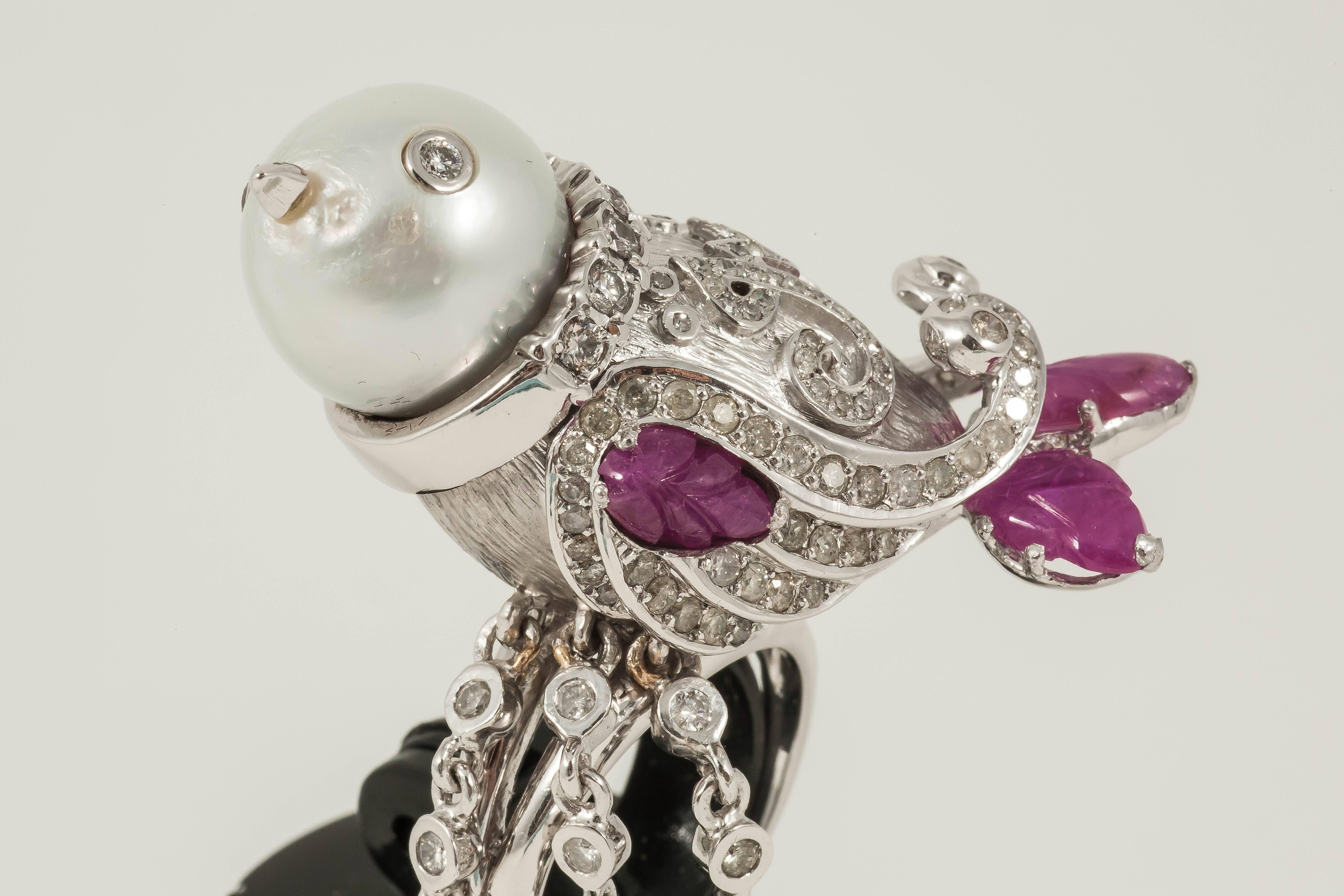 Pearl bird encased with Diamonds & carved Ruby leaves. Hanging off this ring are Arabic letters of love & peace

18K White Gold: 30.1gms
Diamond: 4.8cts
Ruby leaves: 2.6cts
South-Sea Pearl