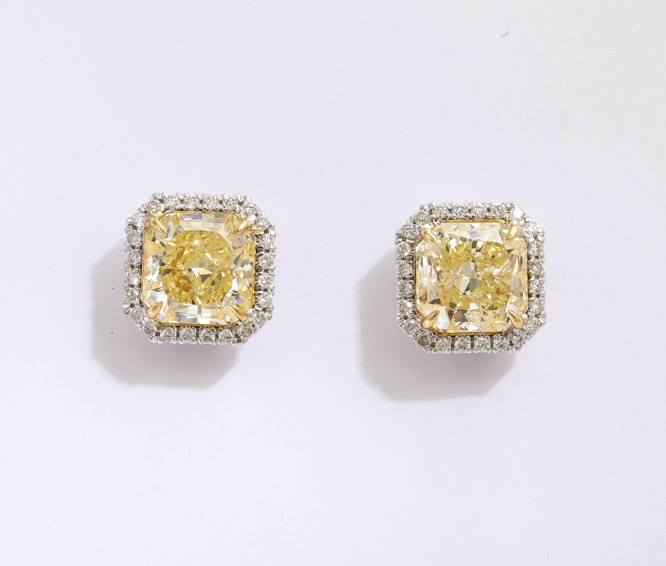 Stunning yellow and white diamond earring studs. The center radiant cut fancy light yellow diamonds are 2.06 cts each, and their clarity is I1. The total weight of diamonds in the earrings is 4.62cts.  The yellow diamonds are cradled in a bed of