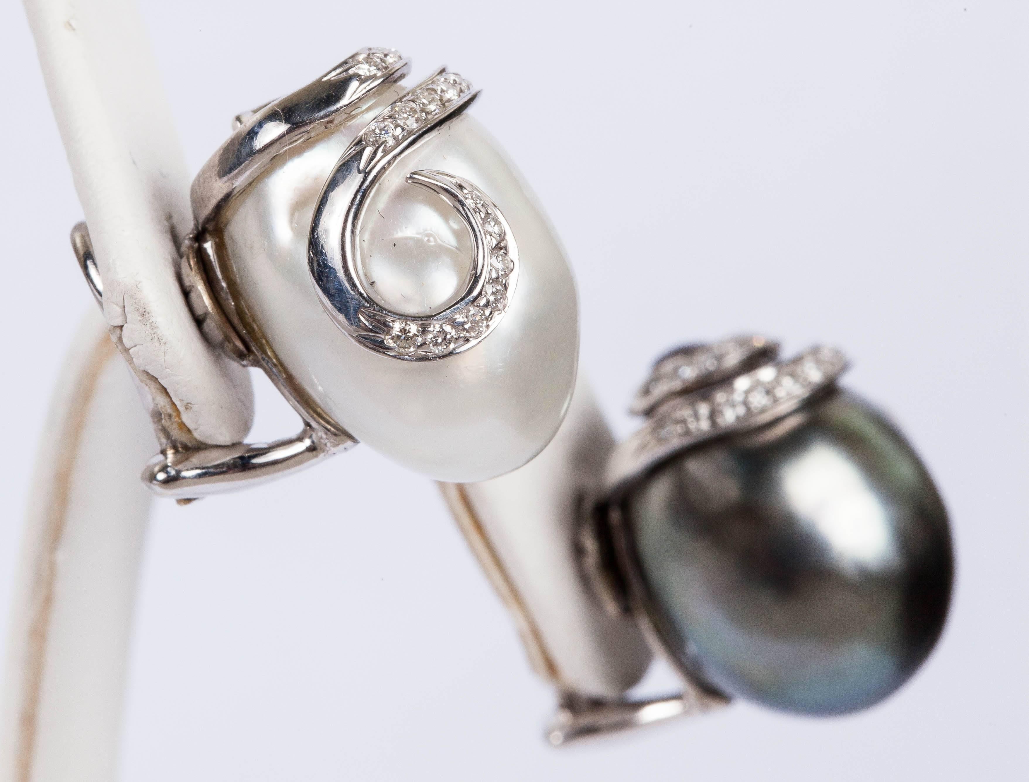 18K white gold clip on earrings with a 17x13mm white South Sea pearl and a 17x13mm Tahitian Baroque pearl. There is a swirl design of 18K white gold with approx. 0.30ct  pave set white diamonds adorning the pearls.