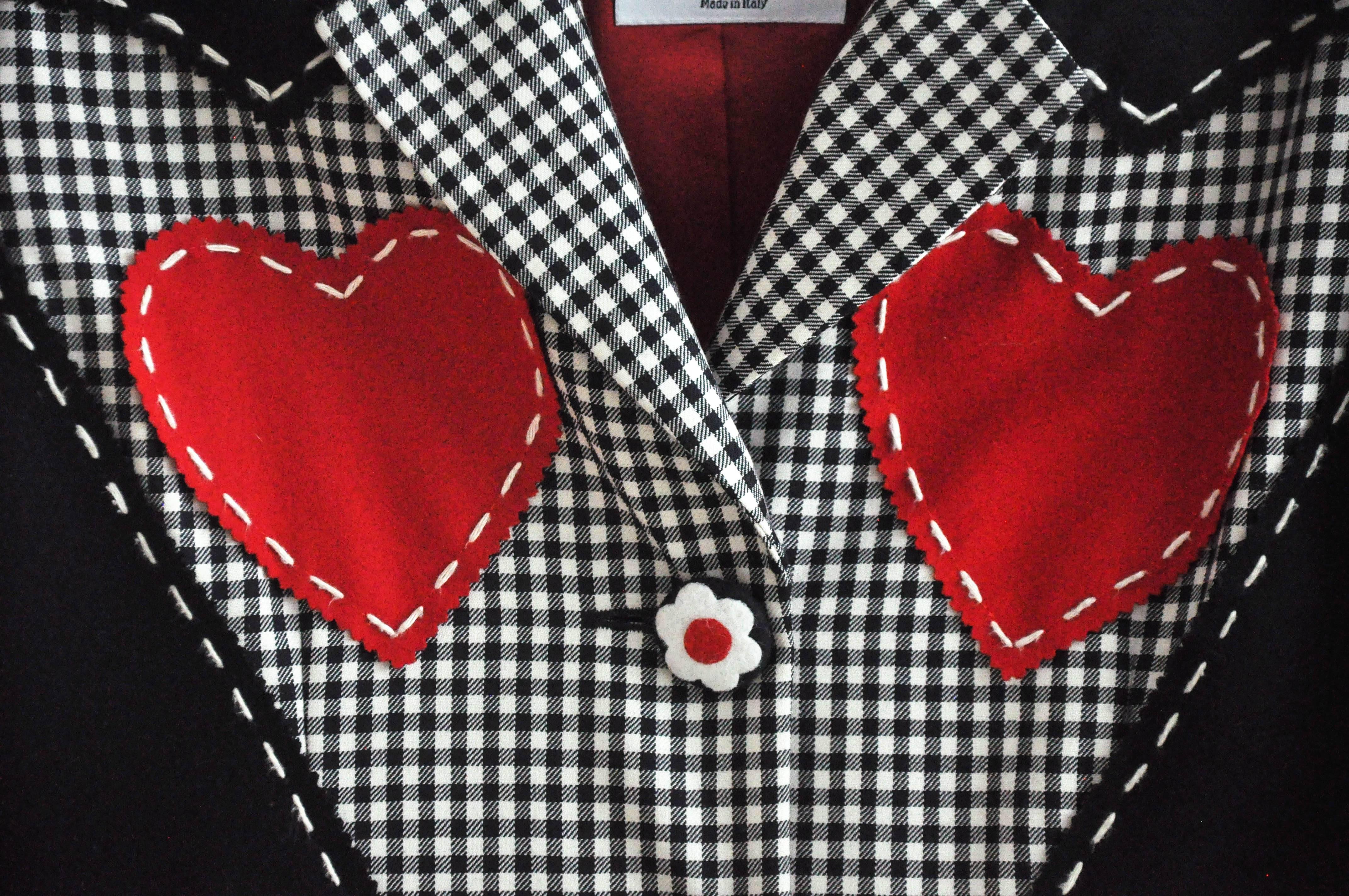 Ein farbenfroher, schwarz-weiß karierter Blazer mit zwei roten Herzen von dem innovativen italienischen Designer Franco Moschino (1950-1994).  Er ist bekannt für seine kühnen, modernen Entwürfe, die oft die High Fashion persiflieren.  Das